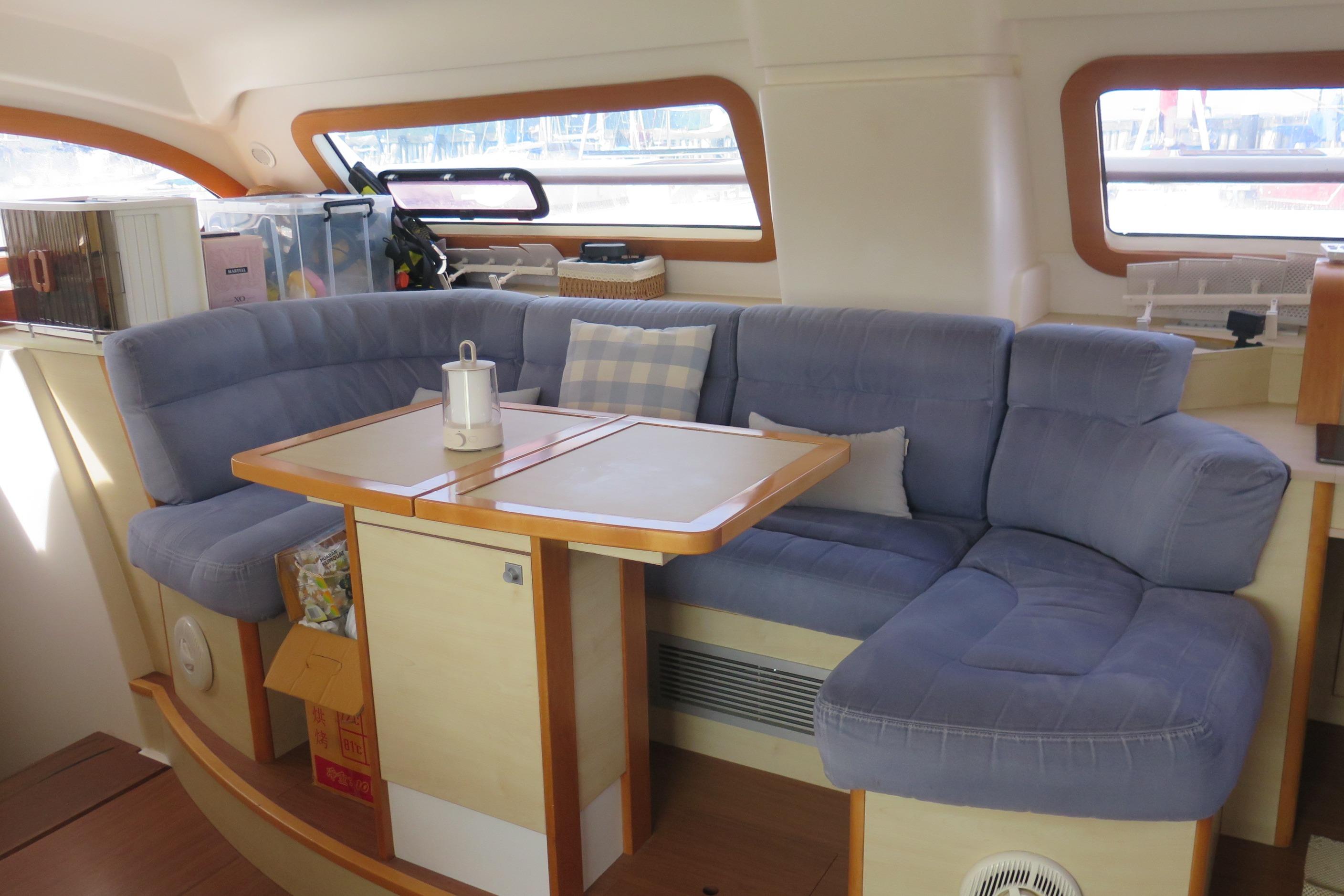 Interior of 2011 Catana 47 yacht with blue cushioned seating and wooden table.