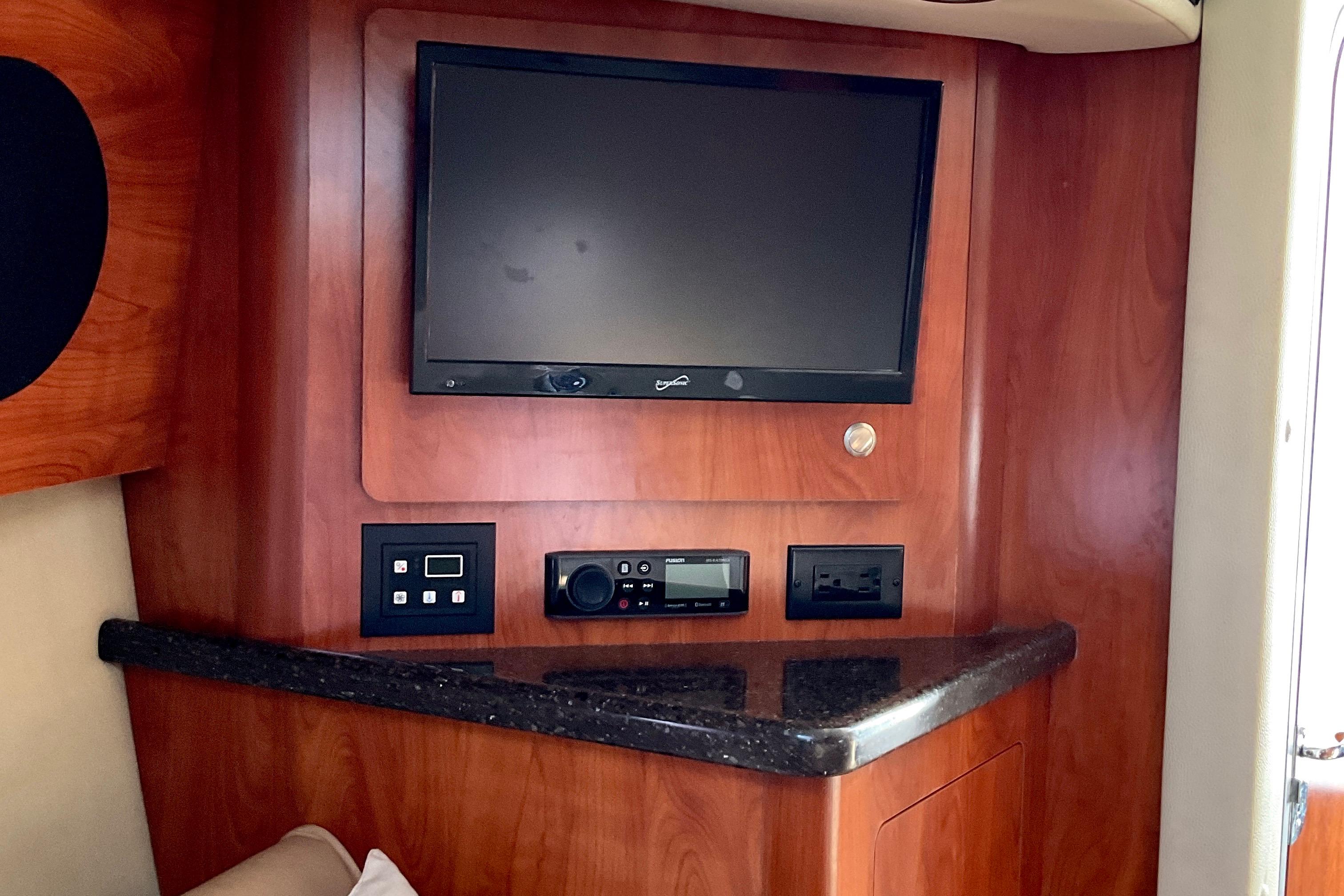 2013 Rinker 290 Express Cruiser interior with TV and control panel on wood finish.