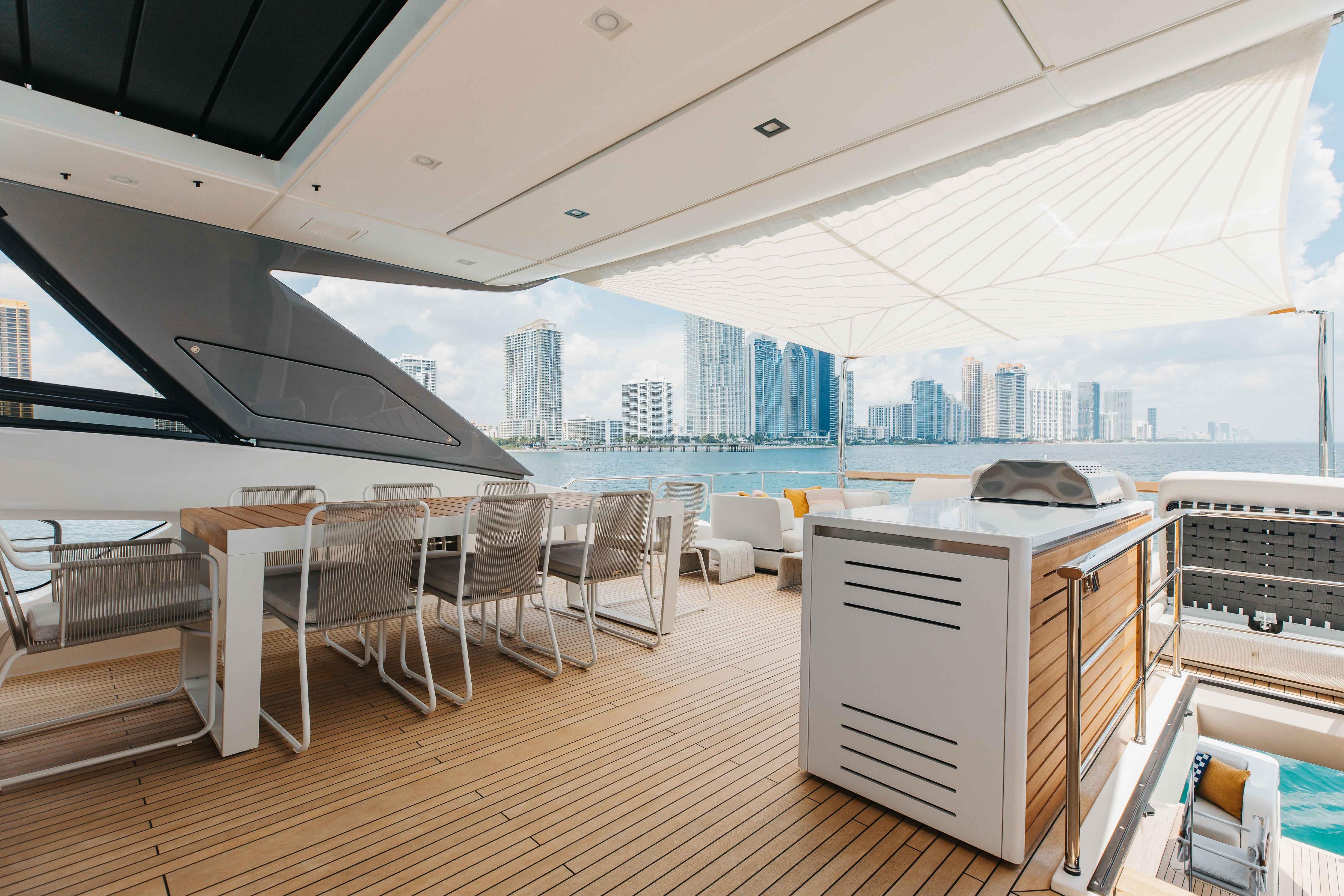 Luxurious 2024 Sanlorenzo SL90A yacht deck with dining area, city skyline view.