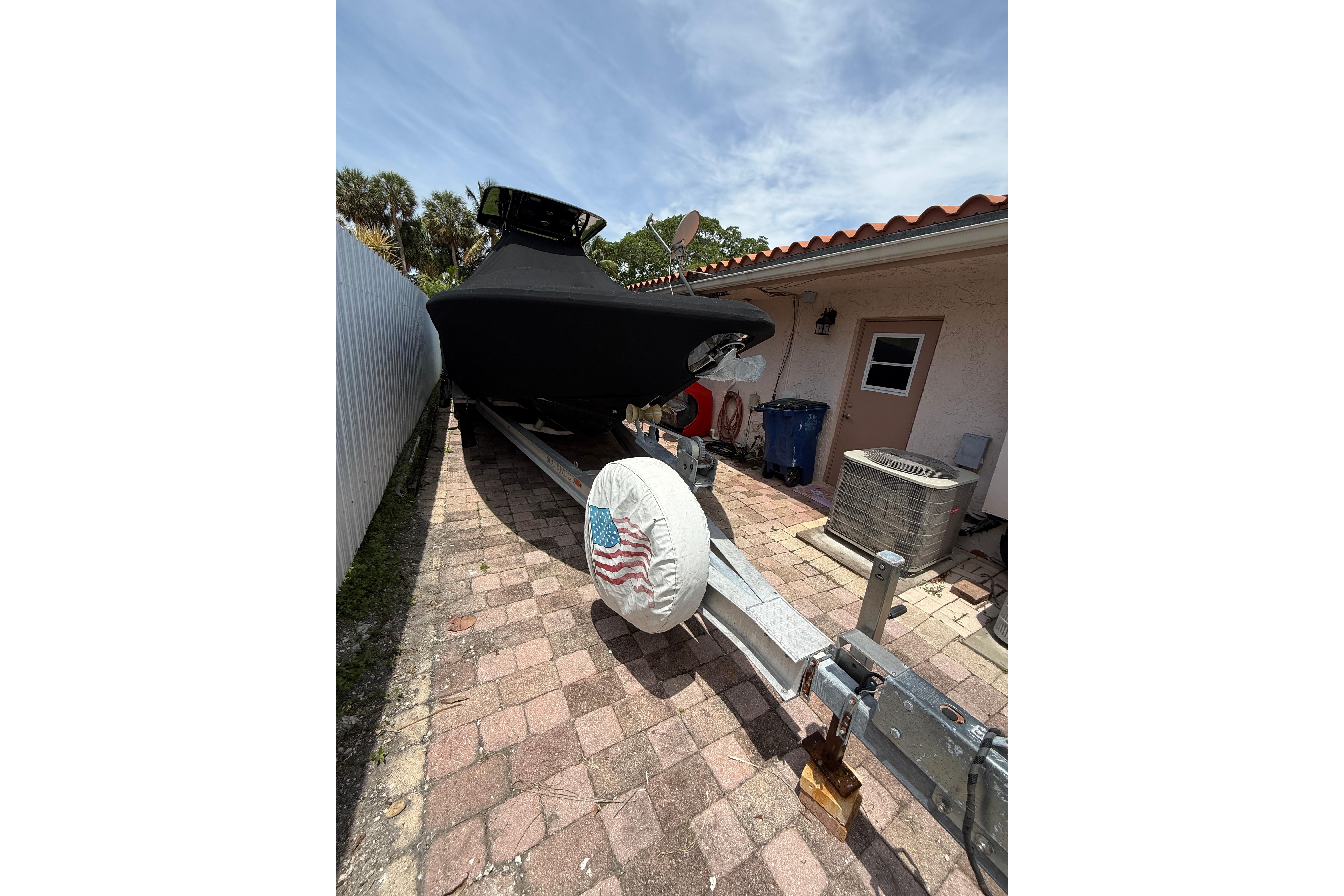 Covered 2015 Blackwood 27 boat on trailer in driveway, American flag tire cover.