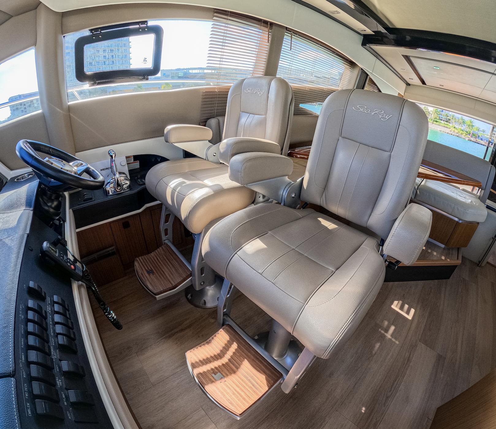 Luxurious 2018 Sea Ray L590 yacht interior with plush captain's chairs and modern helm.