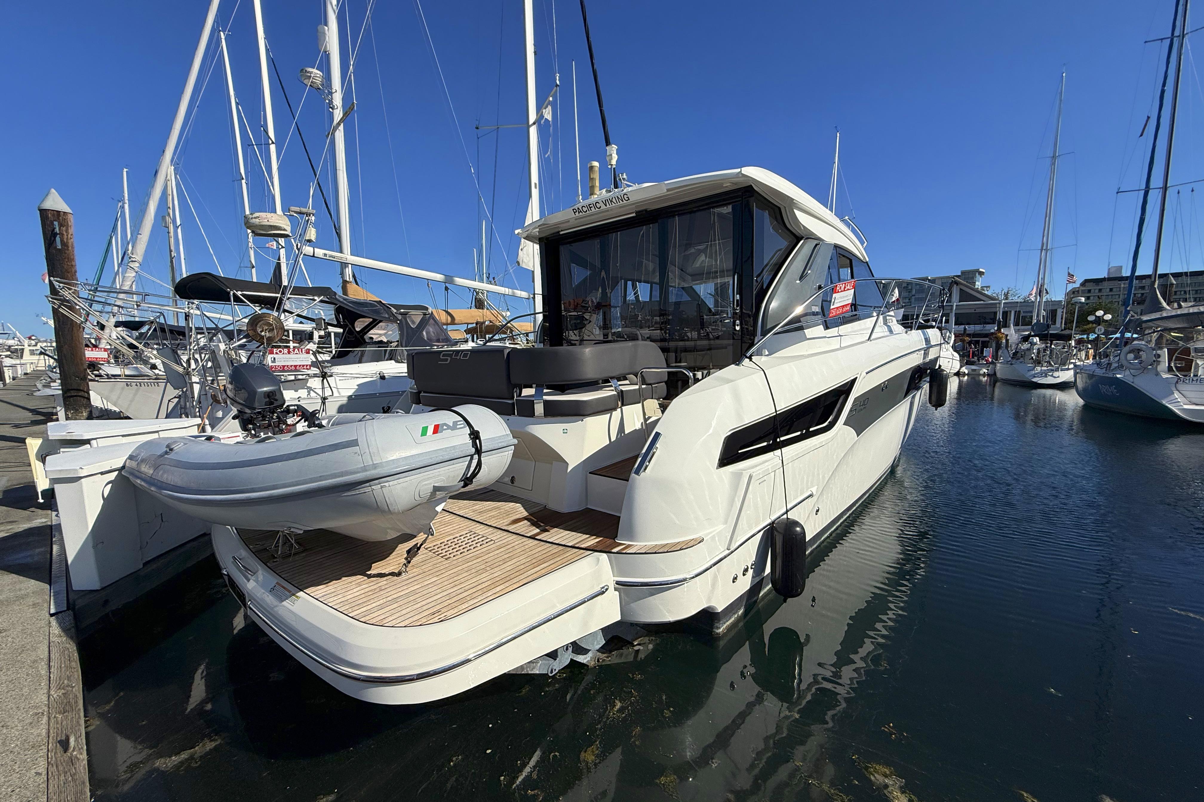 2019 Bavaria S40 HT yacht docked with inflatable boat, clear sky, marina setting.