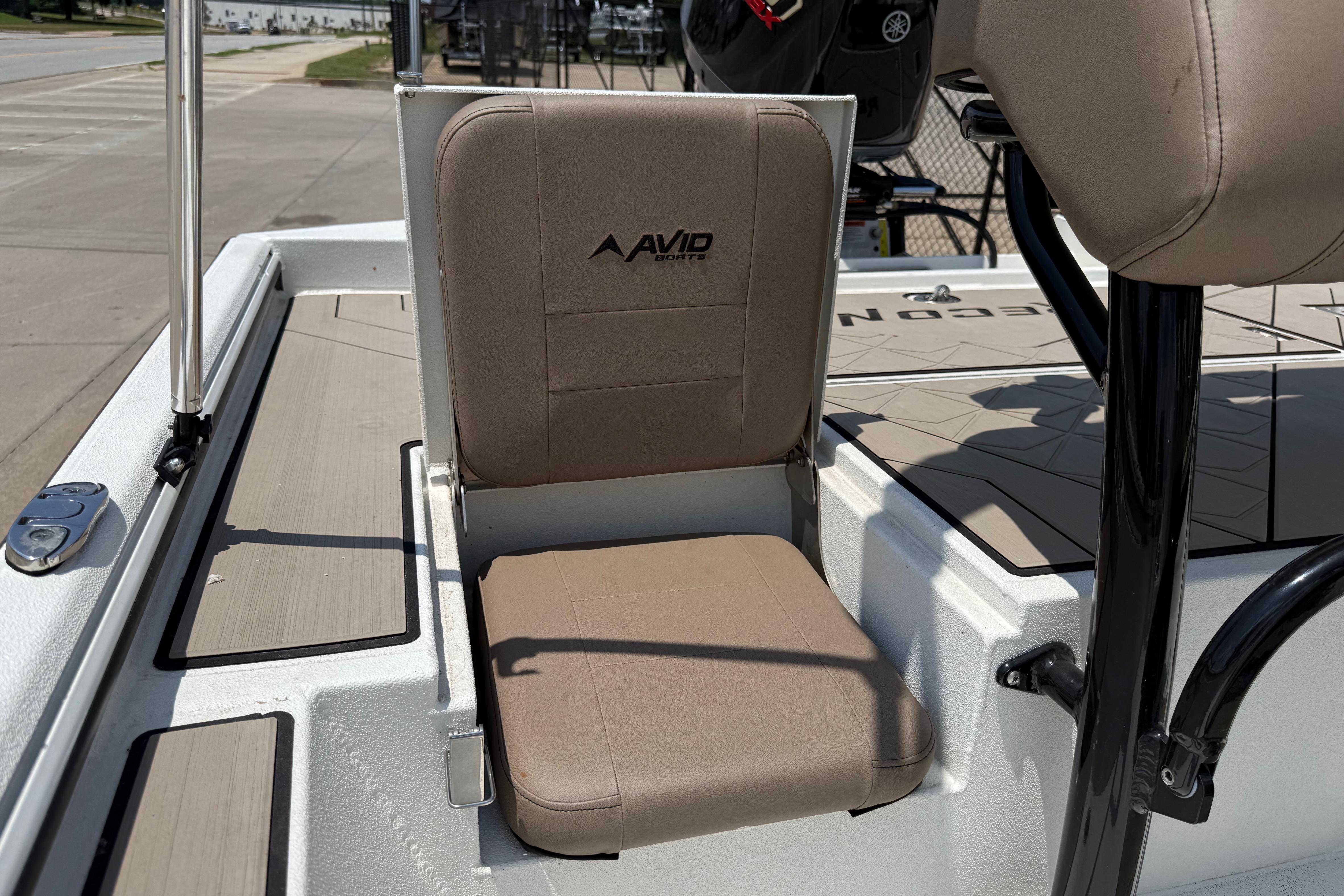 Avid 22 Recon 2025 boat seat with beige upholstery and logo, dockside view.