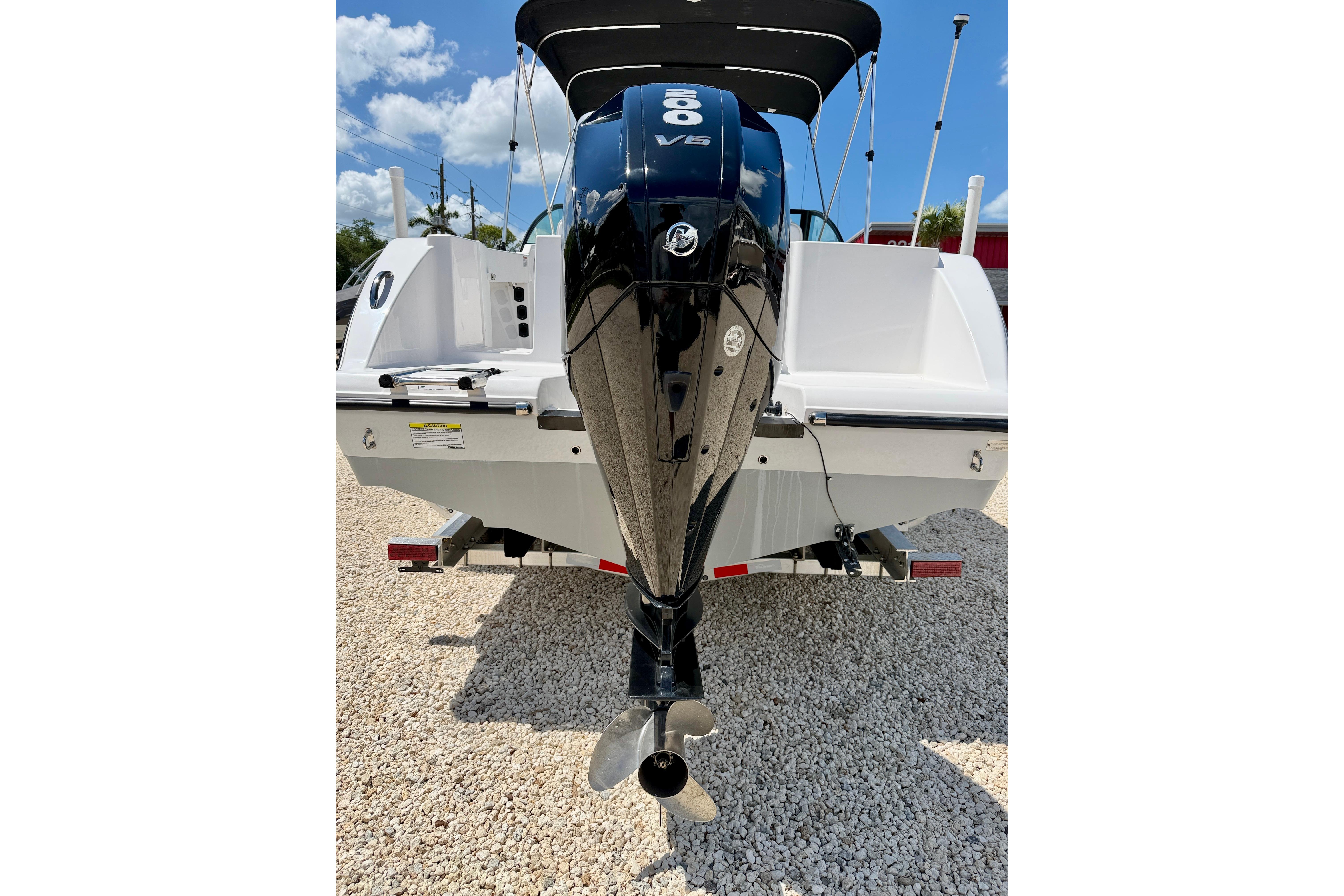 2023 Aquasport 2200 Dual Console boat with powerful outboard motor, parked on gravel.