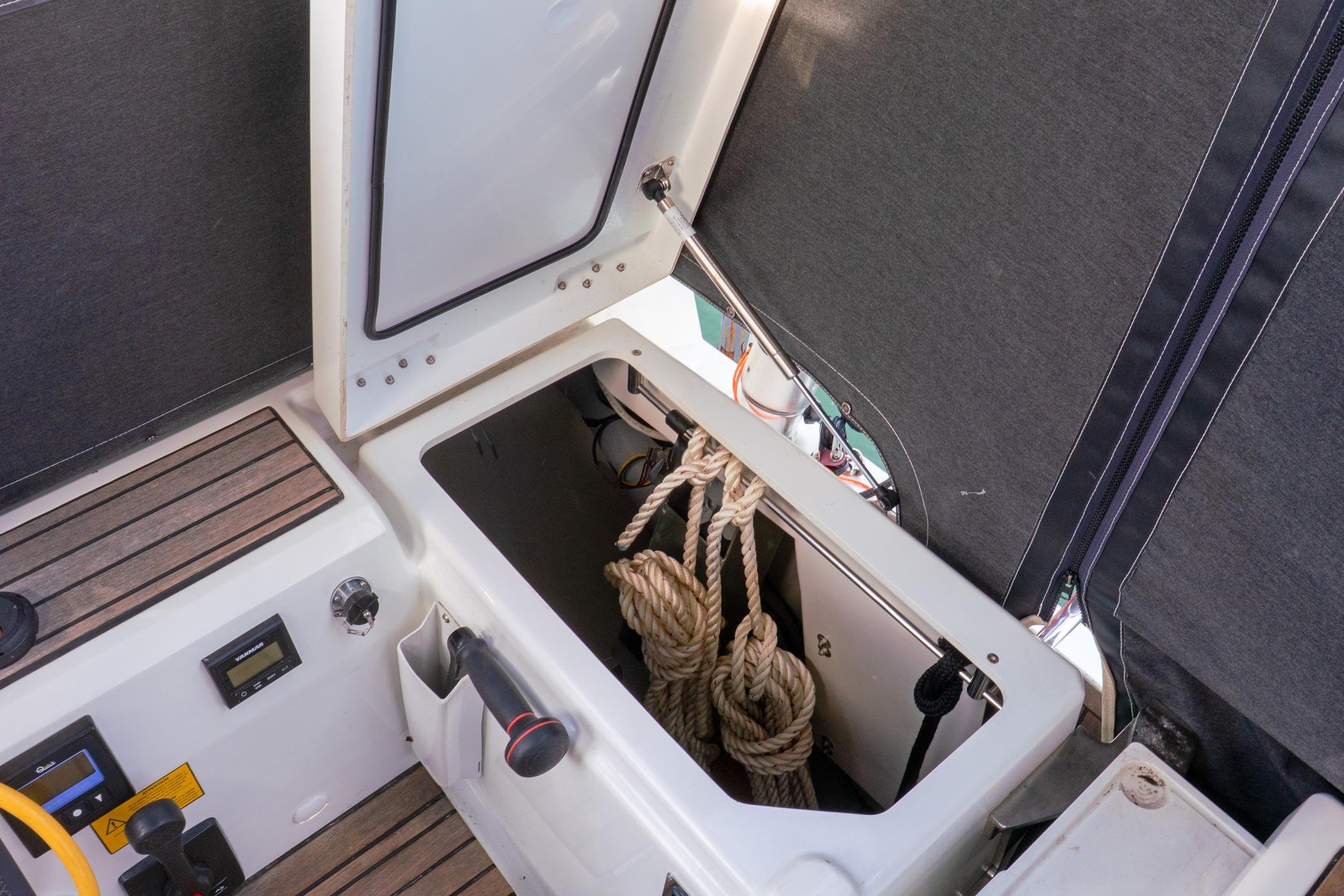Open storage compartment on 2022 Beneteau Oceanis 461 sailboat, showing ropes and controls.