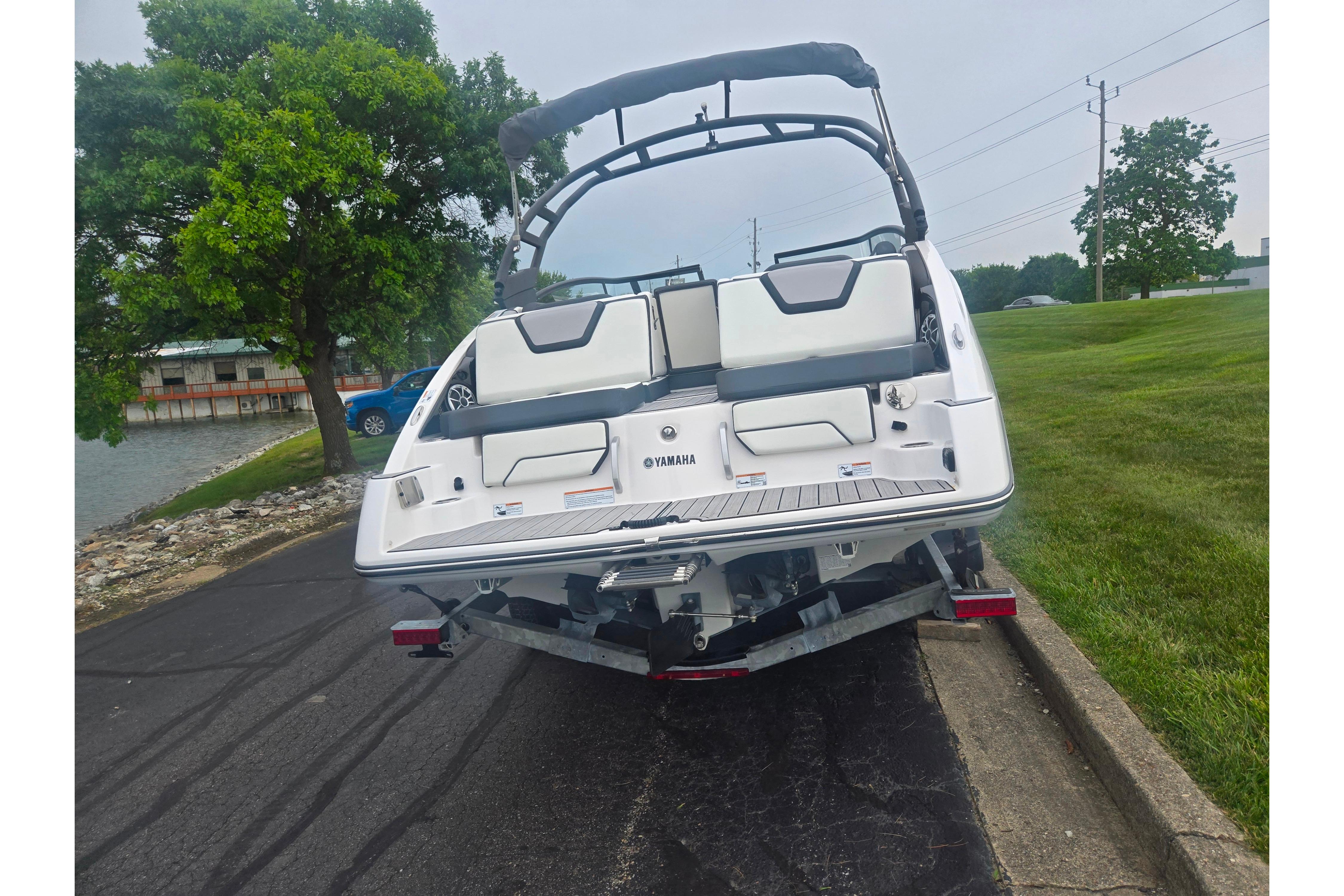 2023 Yamaha Boats 252S on trailer near water, showcasing sleek design and seating.
