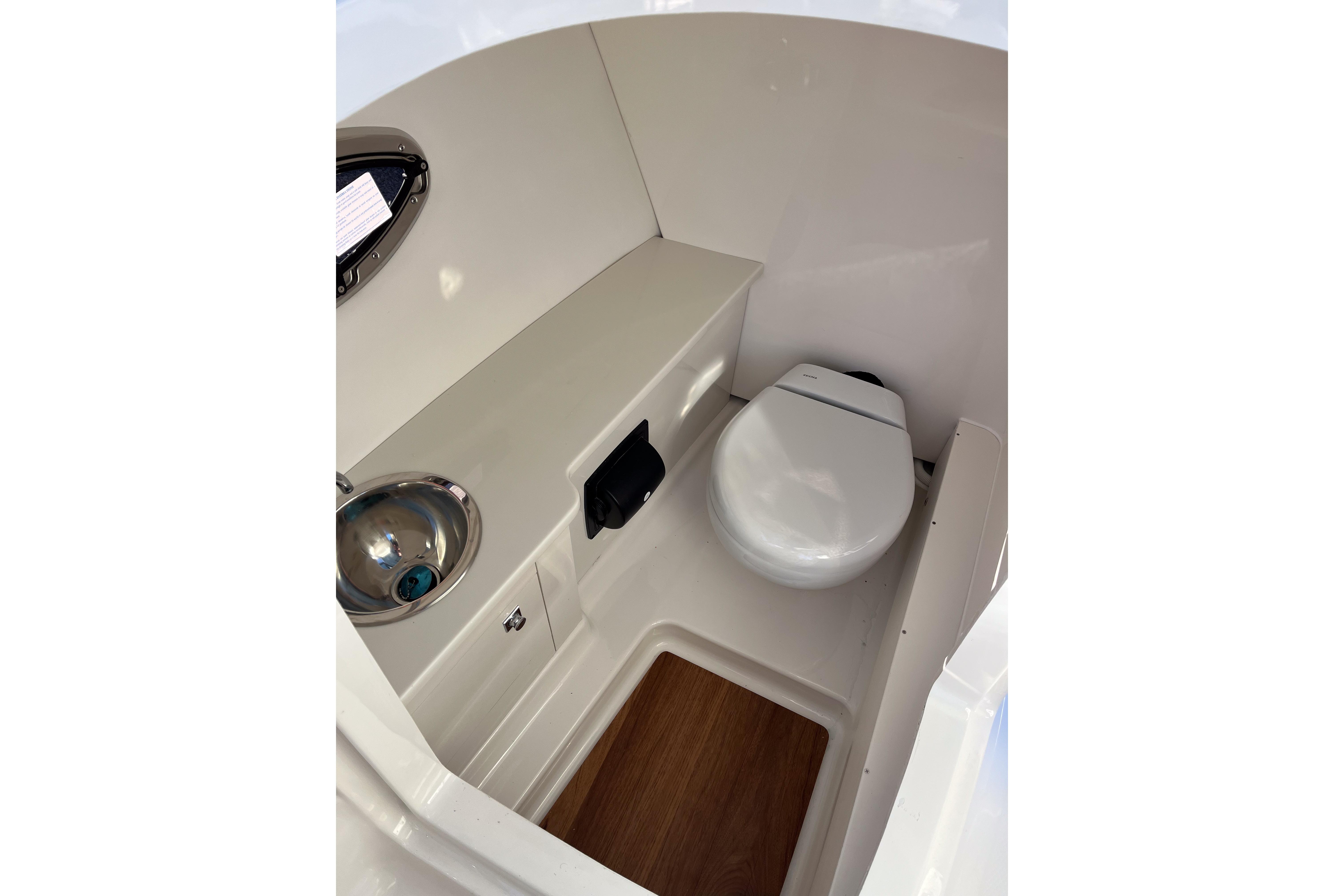 2026 Robalo R257 Dual Console boat interior with compact toilet and sink.