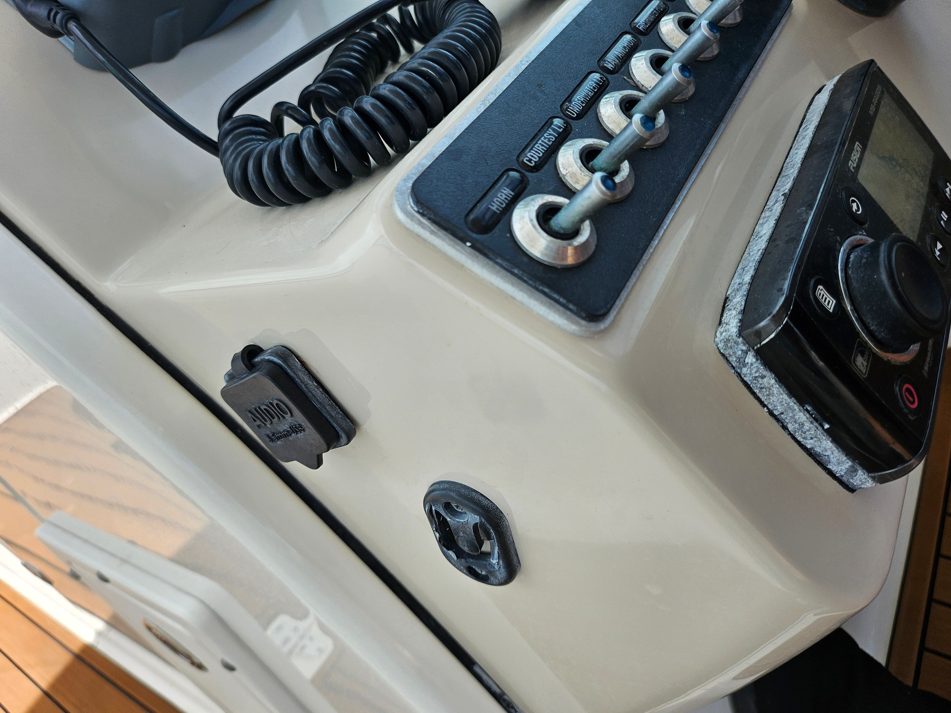 Close-up of a boat control panel with switches and an audio plug.