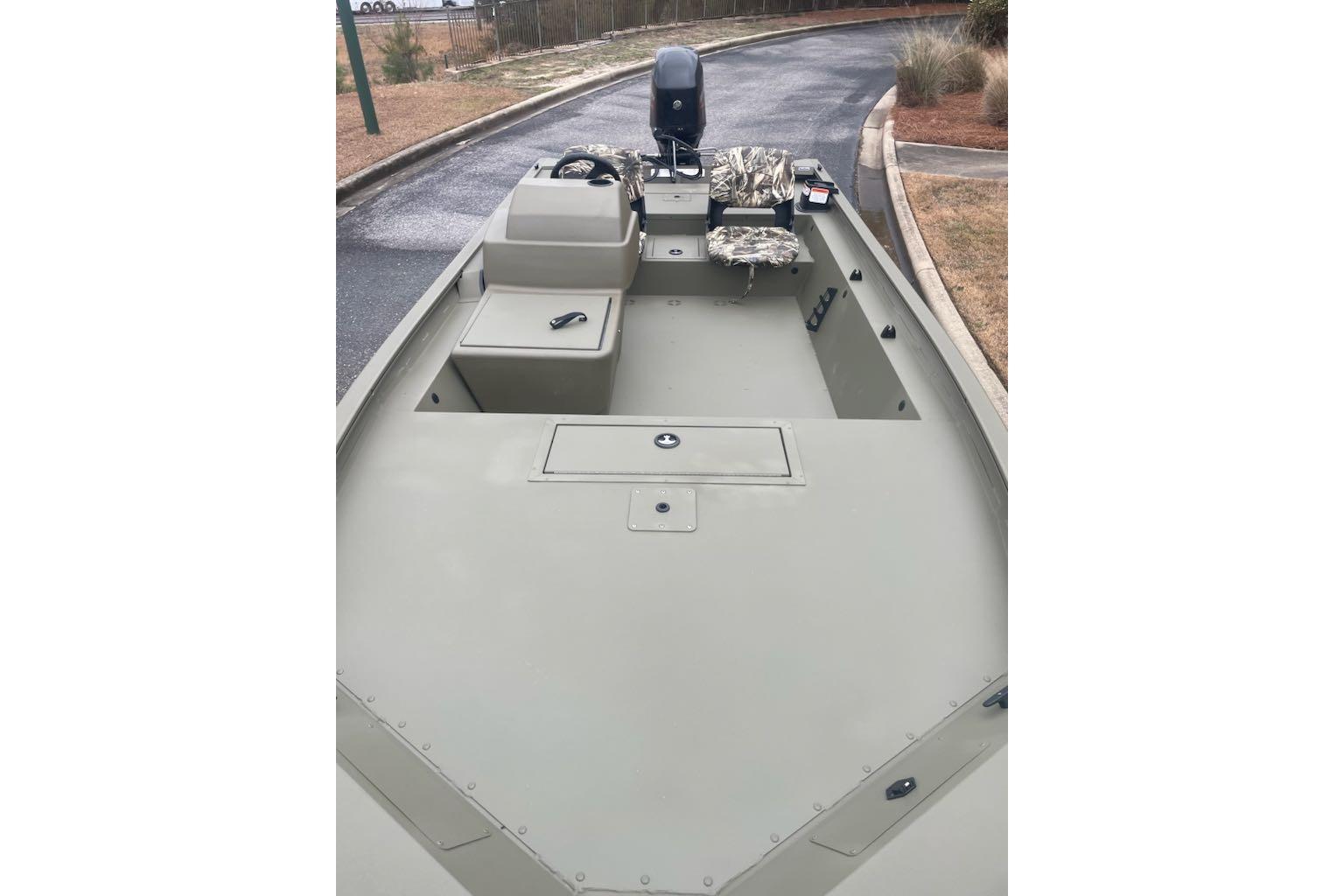 2026 Tracker Grizzly 1754 SC boat with camouflage seating, parked on a paved road.