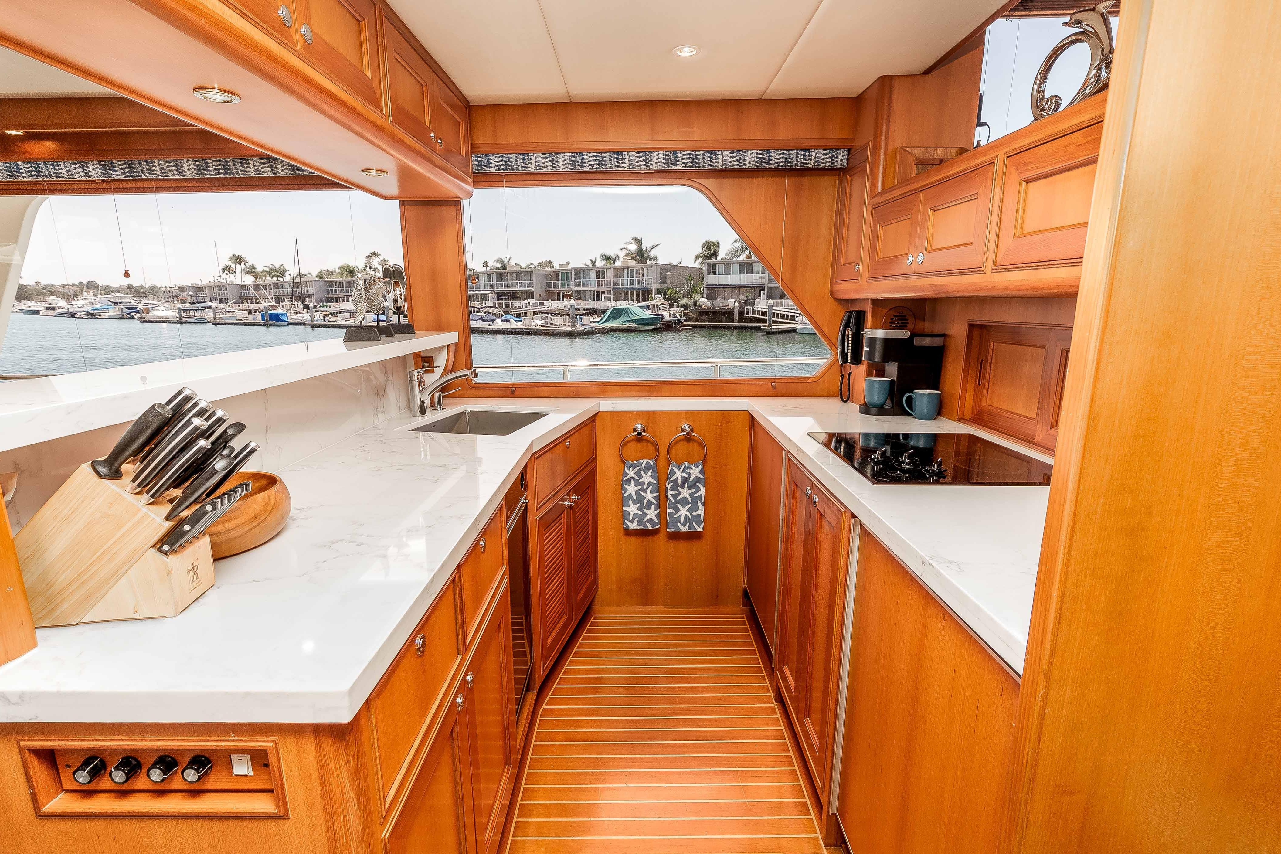 Luxurious 2005 Offshore Yachts 54 Pilothouse kitchen with wood cabinetry and marina view.
