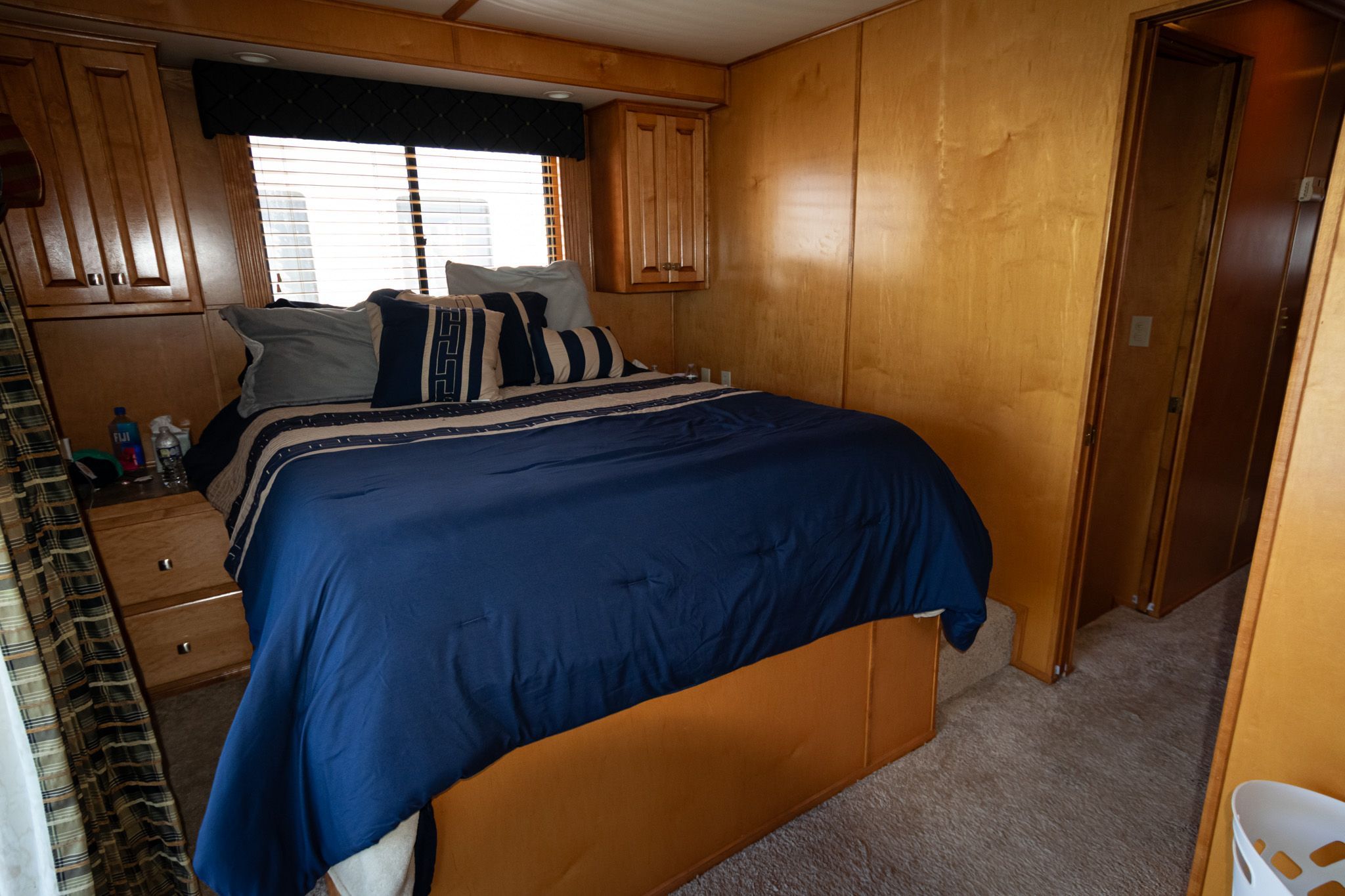 Bedroom in 2003 Lakeview 16x70 houseboat with wooden furnishings and blue bedding.