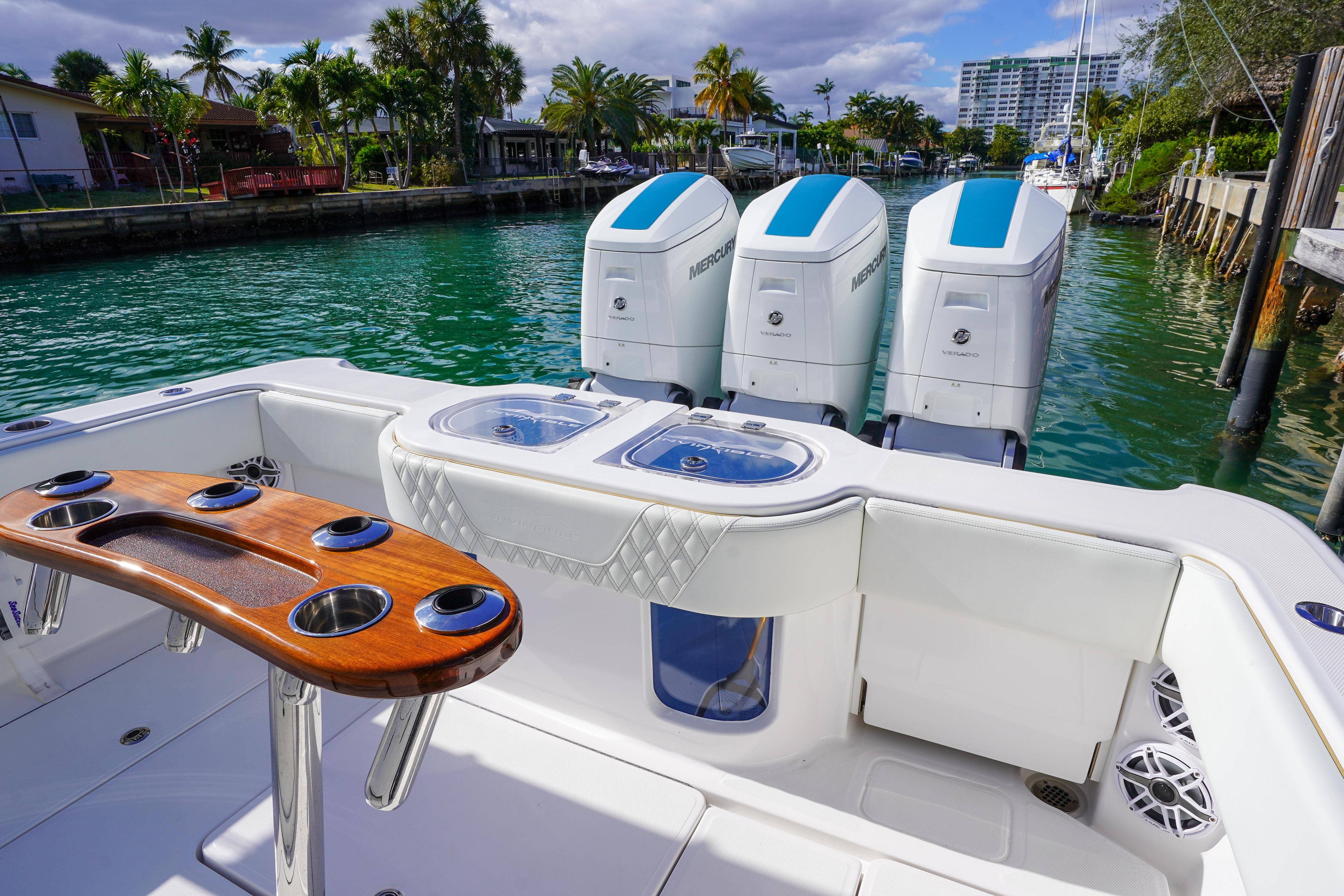 2024 Invincible 43 Open Fisherman boat with triple Mercury engines, docked in a scenic marina.
