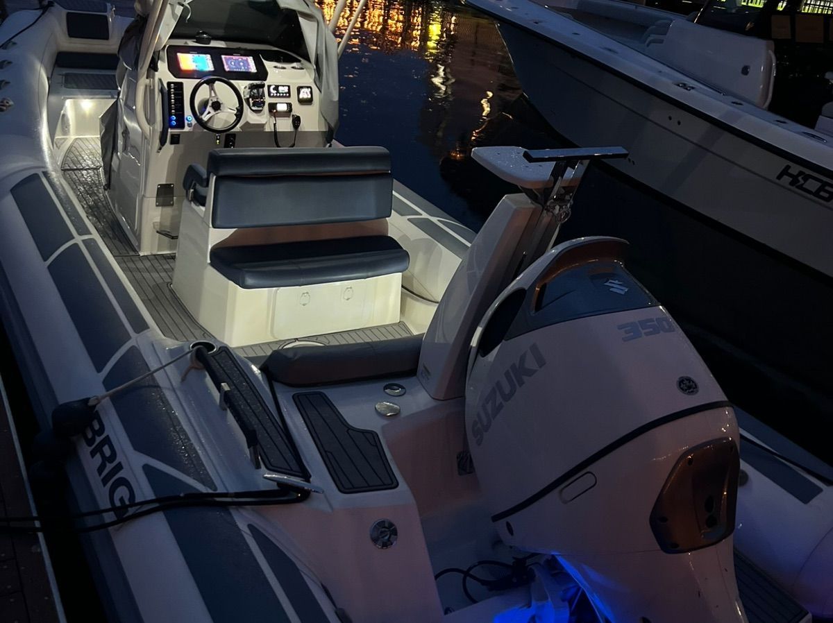A modern inflatable boat with Suzuki engine, illuminated at night, docked.