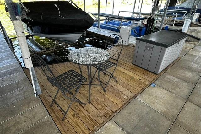 Covered 2007 Four Winns 200 Horizon boat docked beside a patio set on wooden deck.