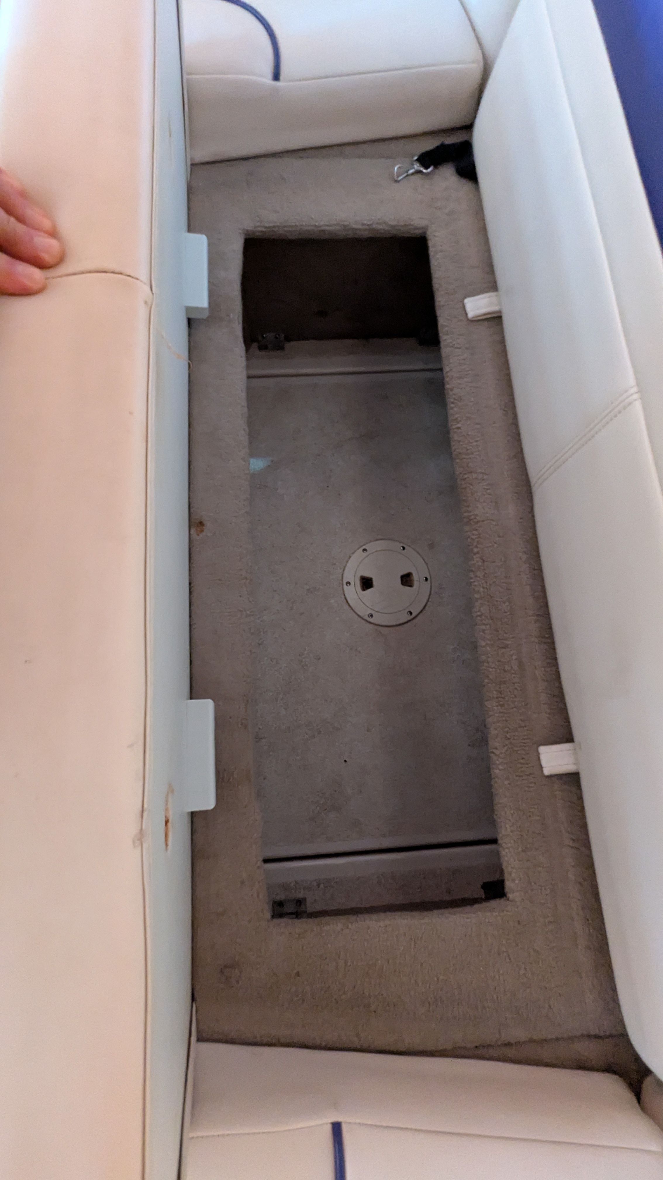 An open storage compartment on a boat with beige carpeting.