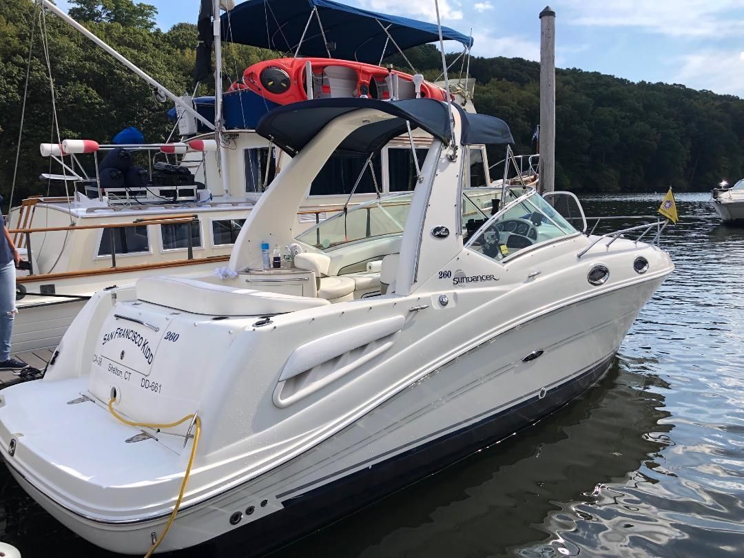 A white 2005 Sea Ray Sundancer 260 boat docked at a pier.