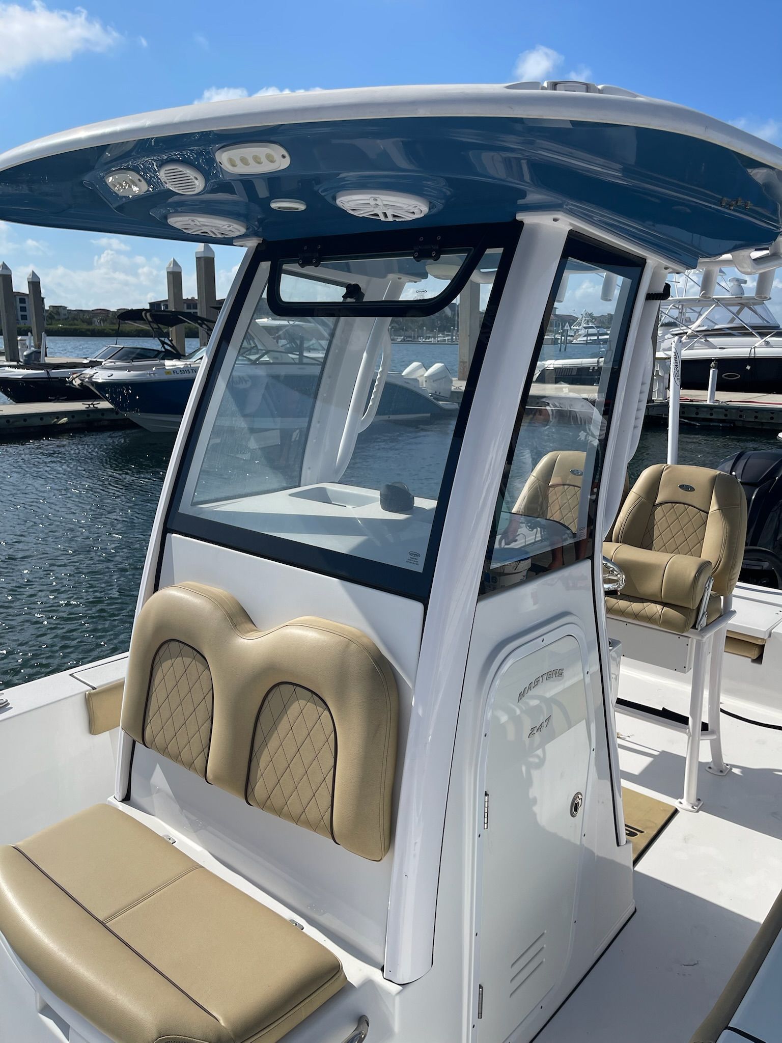 A 2022 Sportsman Masters 247 Bay Boat docked at a marina. It features beige seating and a blue roof.