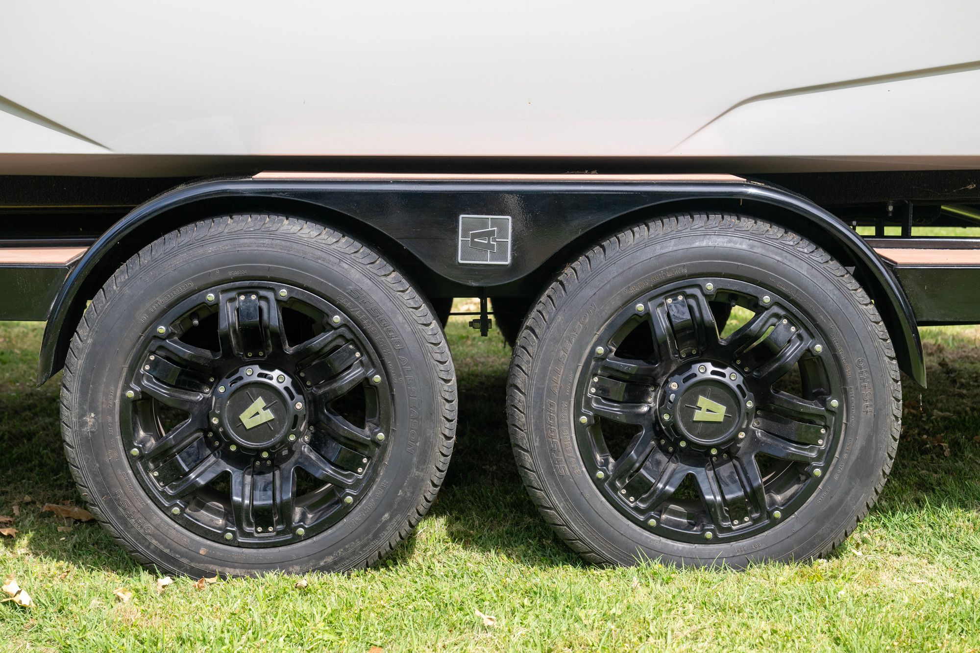Close-up of two black wheels of a boat trailer on grass.