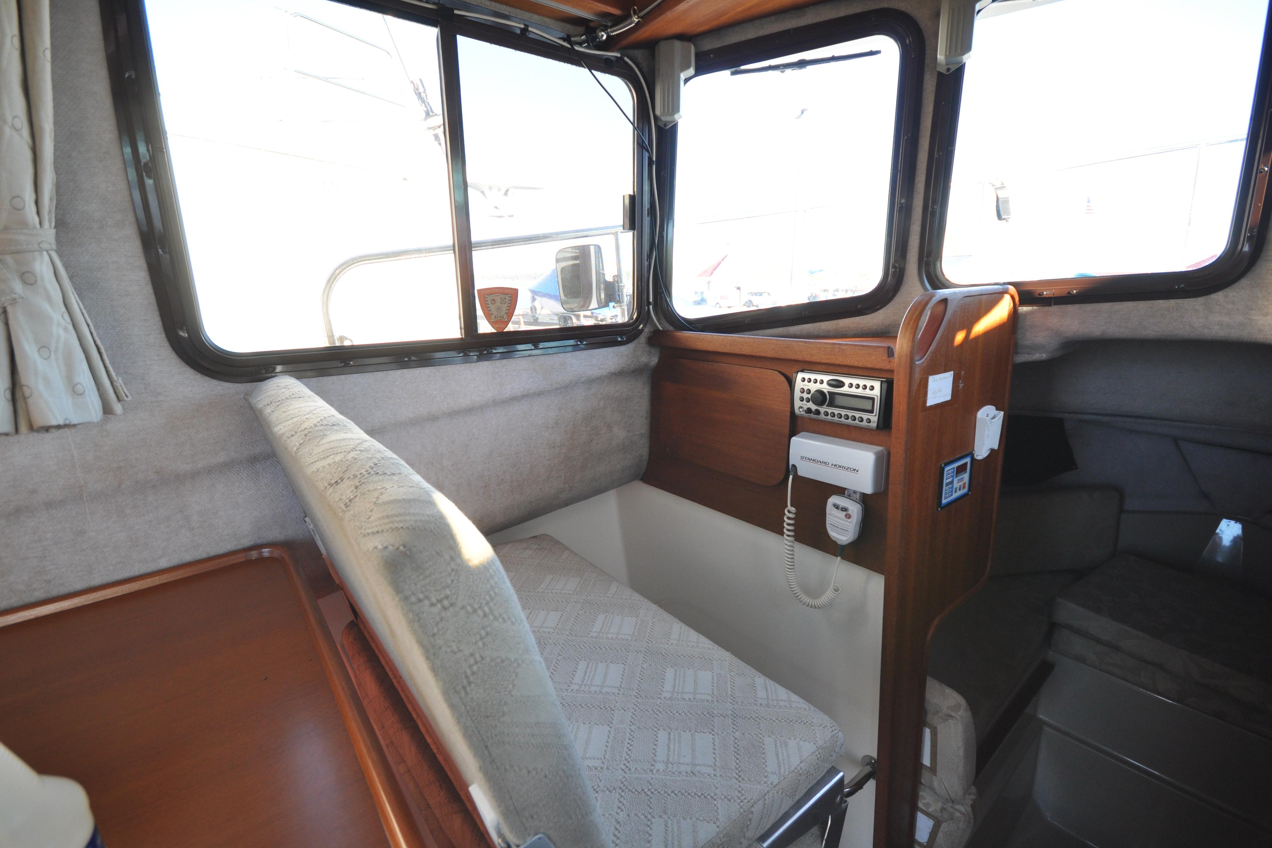 Interior of a 2007 Ranger Tug R-25 boat, featuring a cozy seating area and control panel.