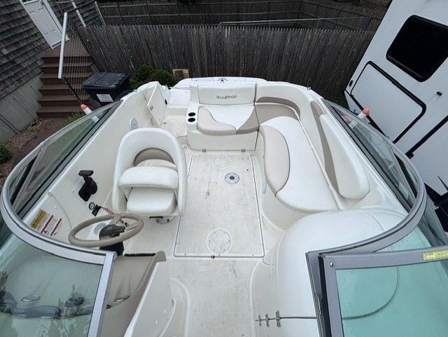 The image shows the cockpit of a 2003 Glastron DX 235 boat with white seating.