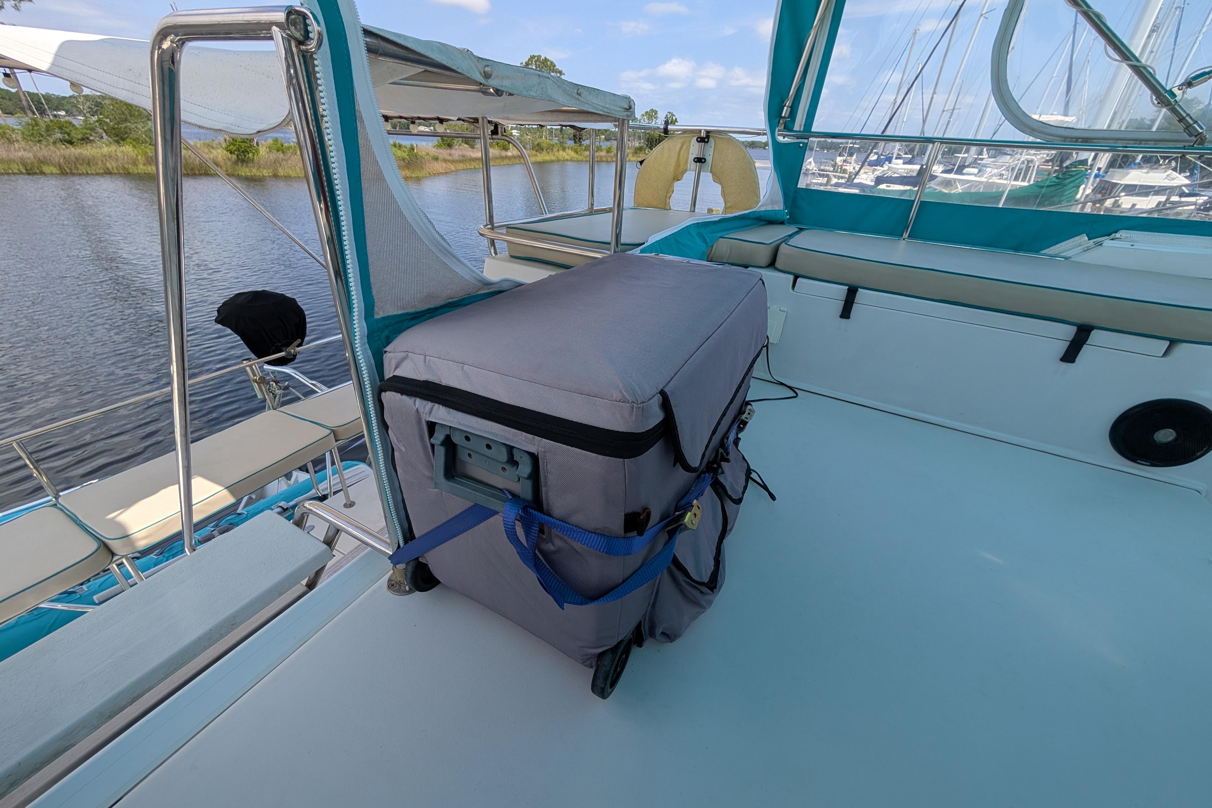 2004 PDQ 34 Powercat deck with covered equipment and scenic marina view.
