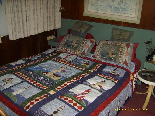 Quilted bedspread with lighthouse design in a cozy bedroom on a 1980 Pluckebaum Baymaster.