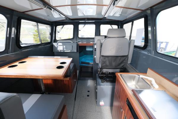 Interior of 2024 Hewescraft 250 Explorer boat, featuring seating, table, and kitchenette.