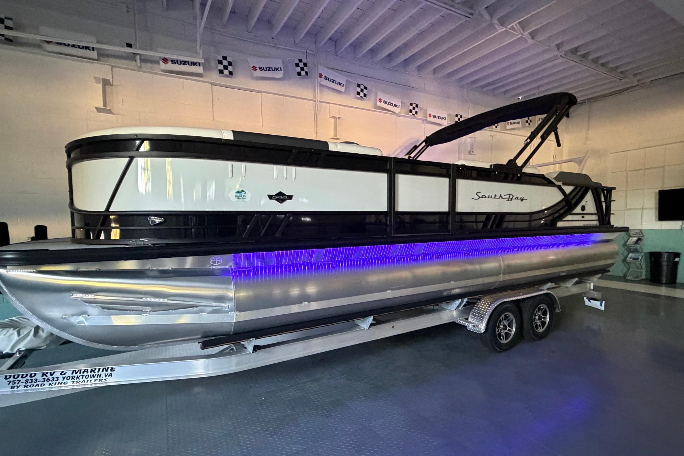 2026 South Bay 525SB2 pontoon boat with trailer, displayed indoors.