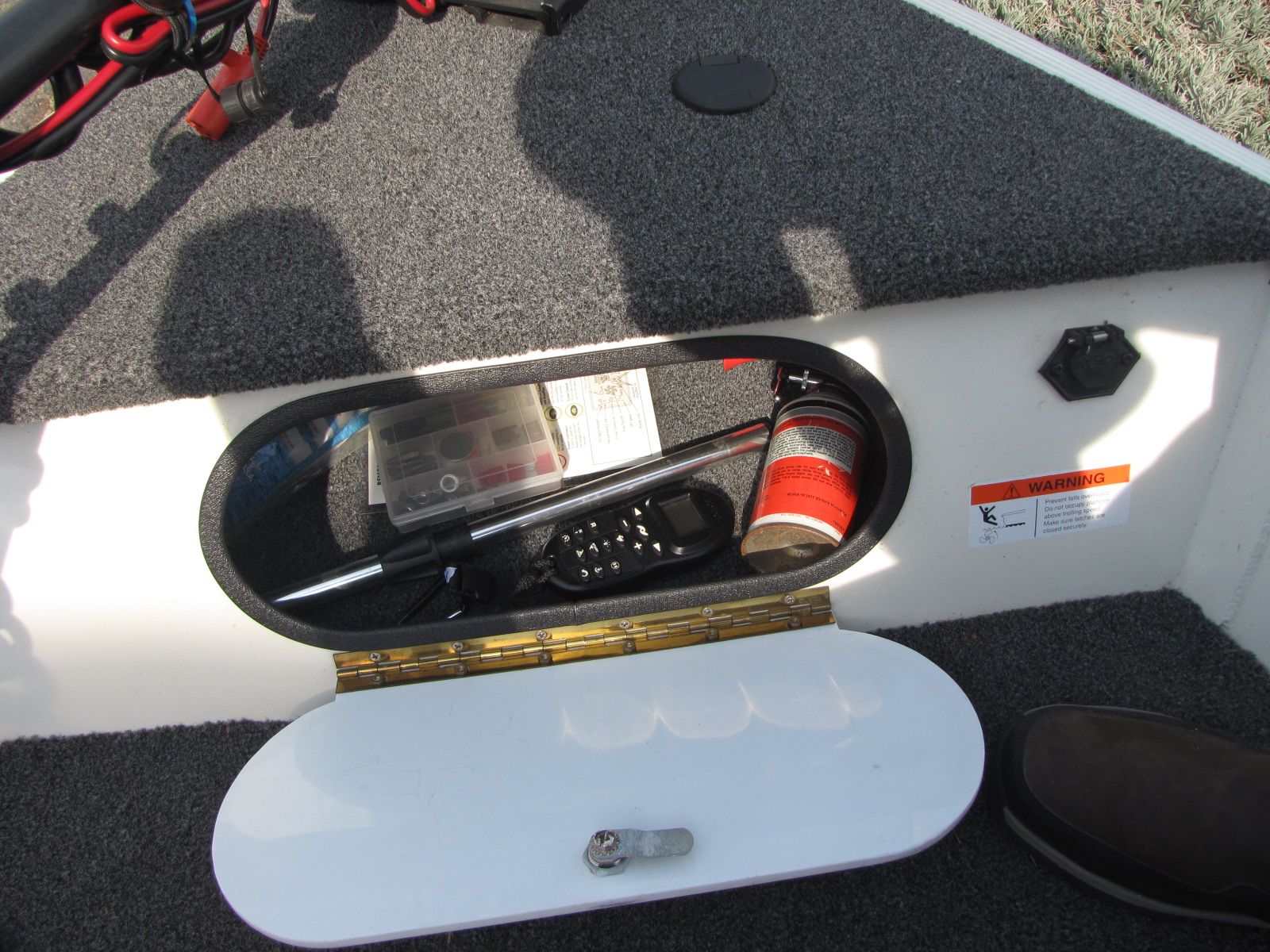 An open storage compartment in a boat with tools and accessories.