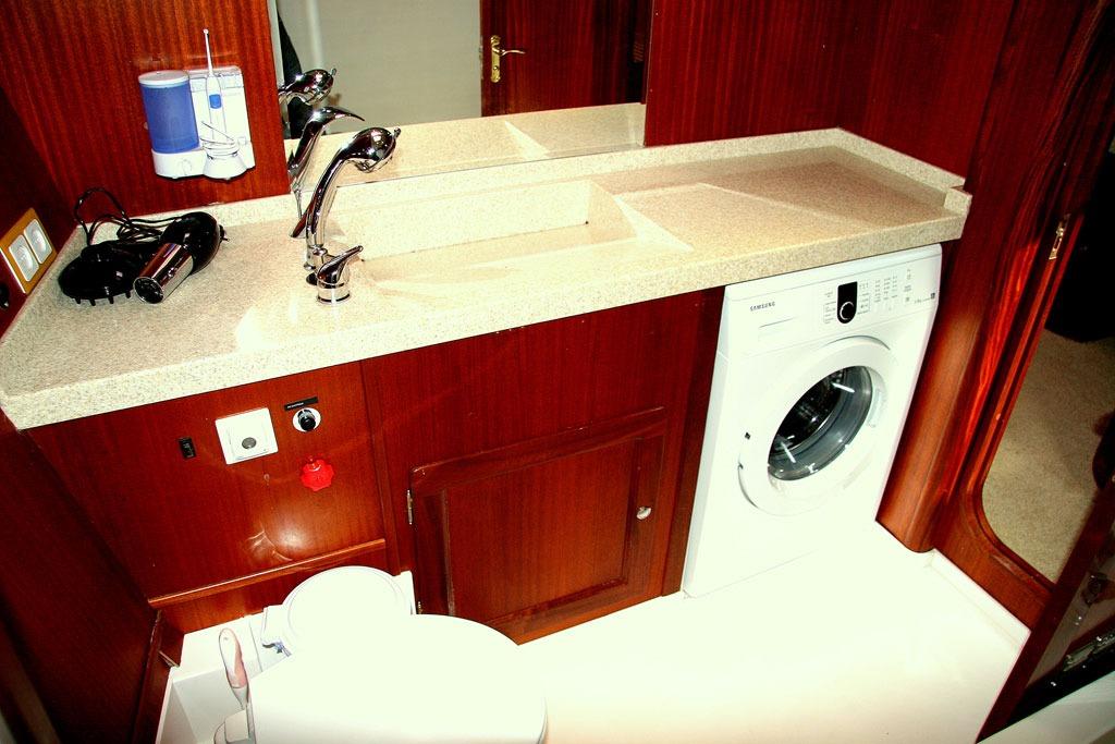 Laundry area with sink, washing machine, and wooden cabinetry in a 2006 BSY 57 yacht.