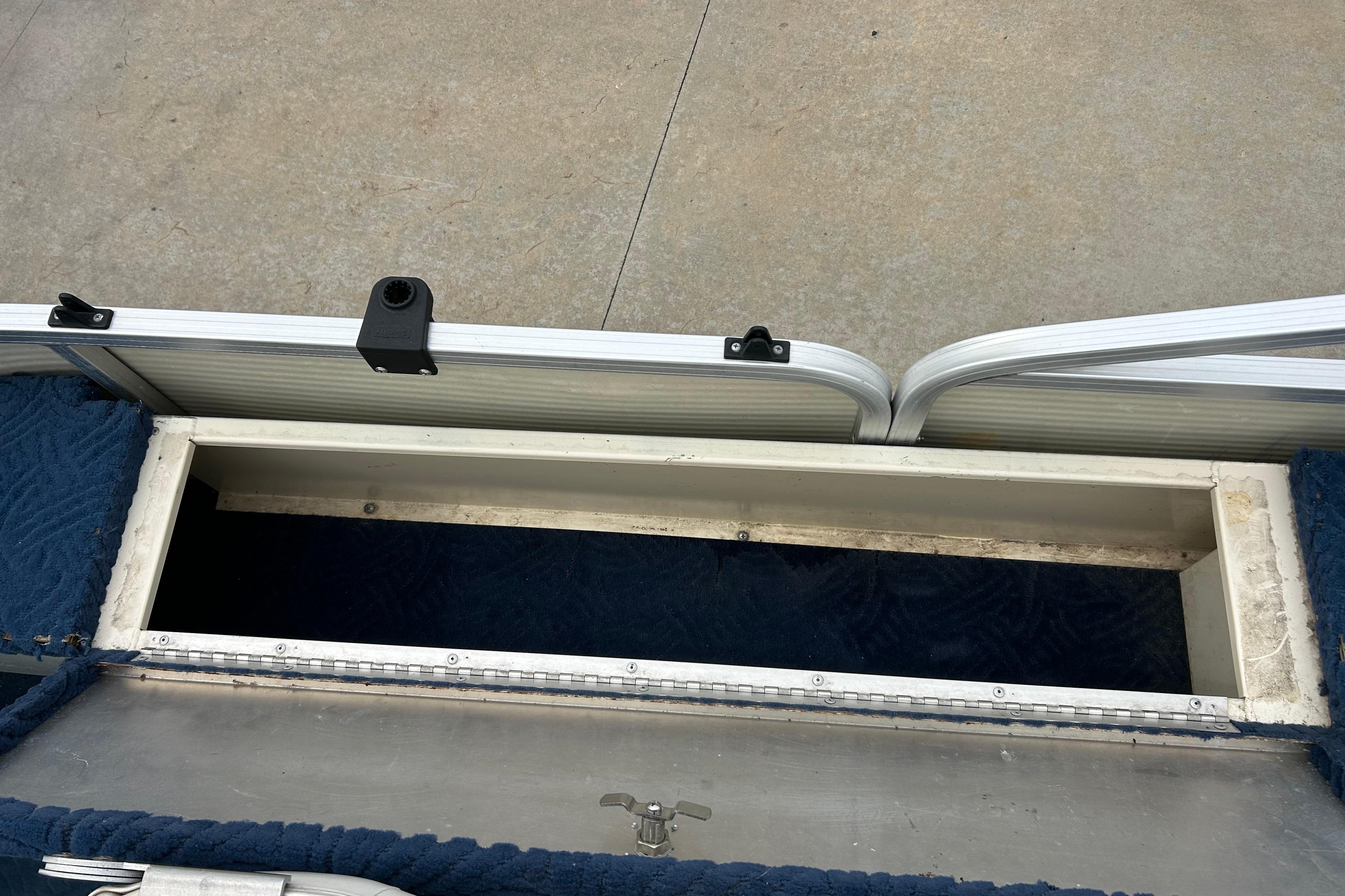 Open storage compartment on a 2002 Lowe Trinidad 200 boat, with blue carpet lining.