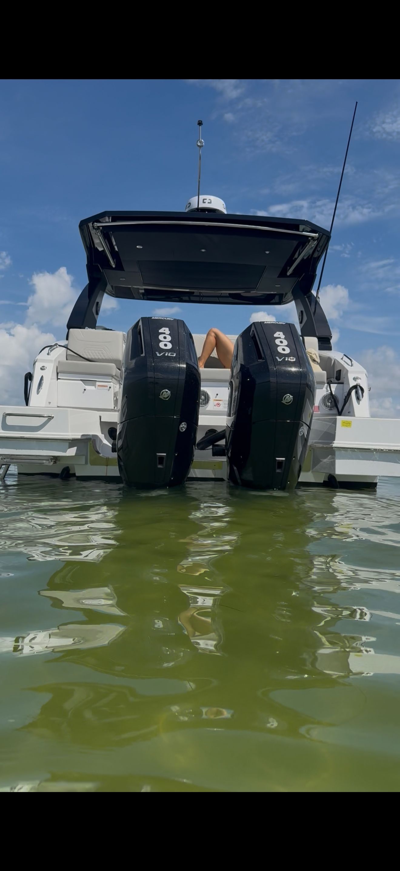 A modern motorboat with two outboard engines in the water. It features a sleek design and spacious platform.