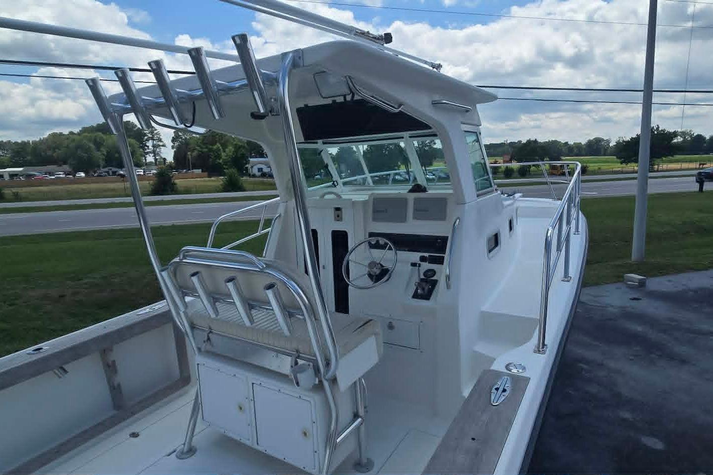 2003 True World Marine 286 boat with helm station, outdoor seating, and rod holders.