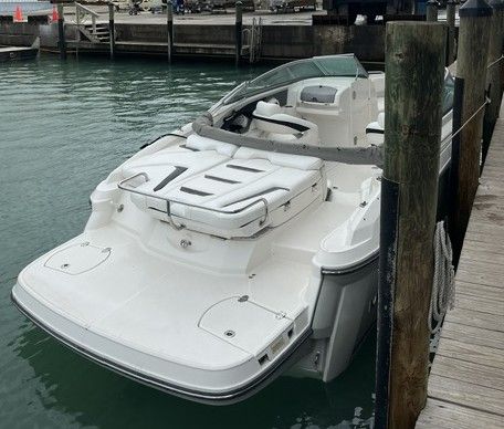 A white sport boat docked, featuring an open cockpit and cushioned seating.