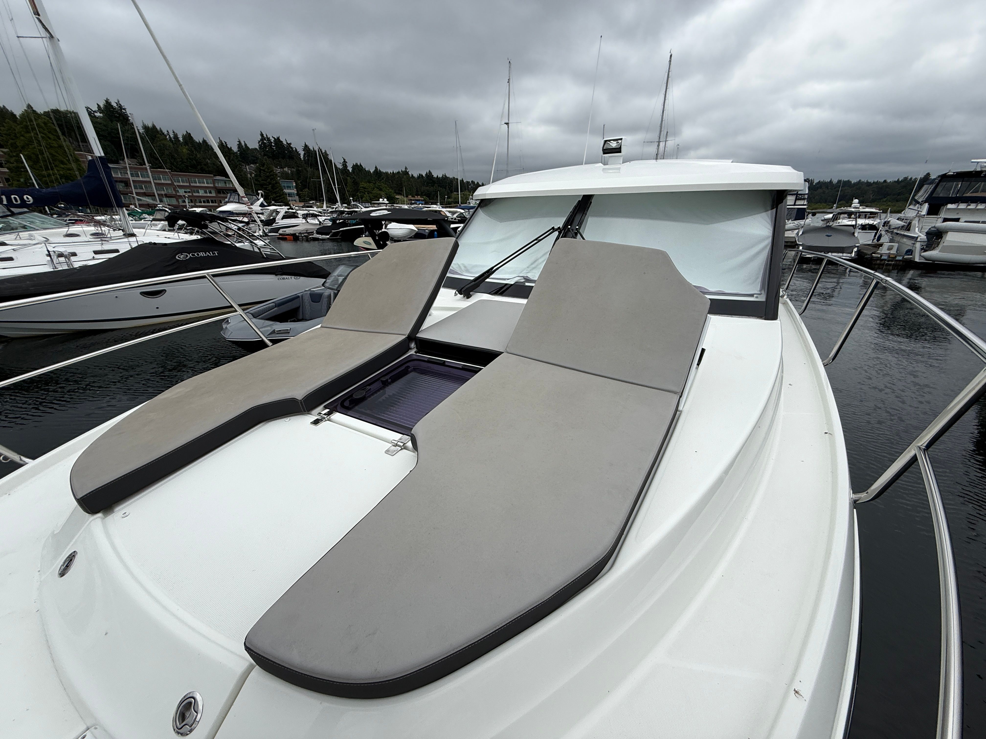 2021 Jeanneau NC 1095 at a marina with gray sun loungers on the deck.