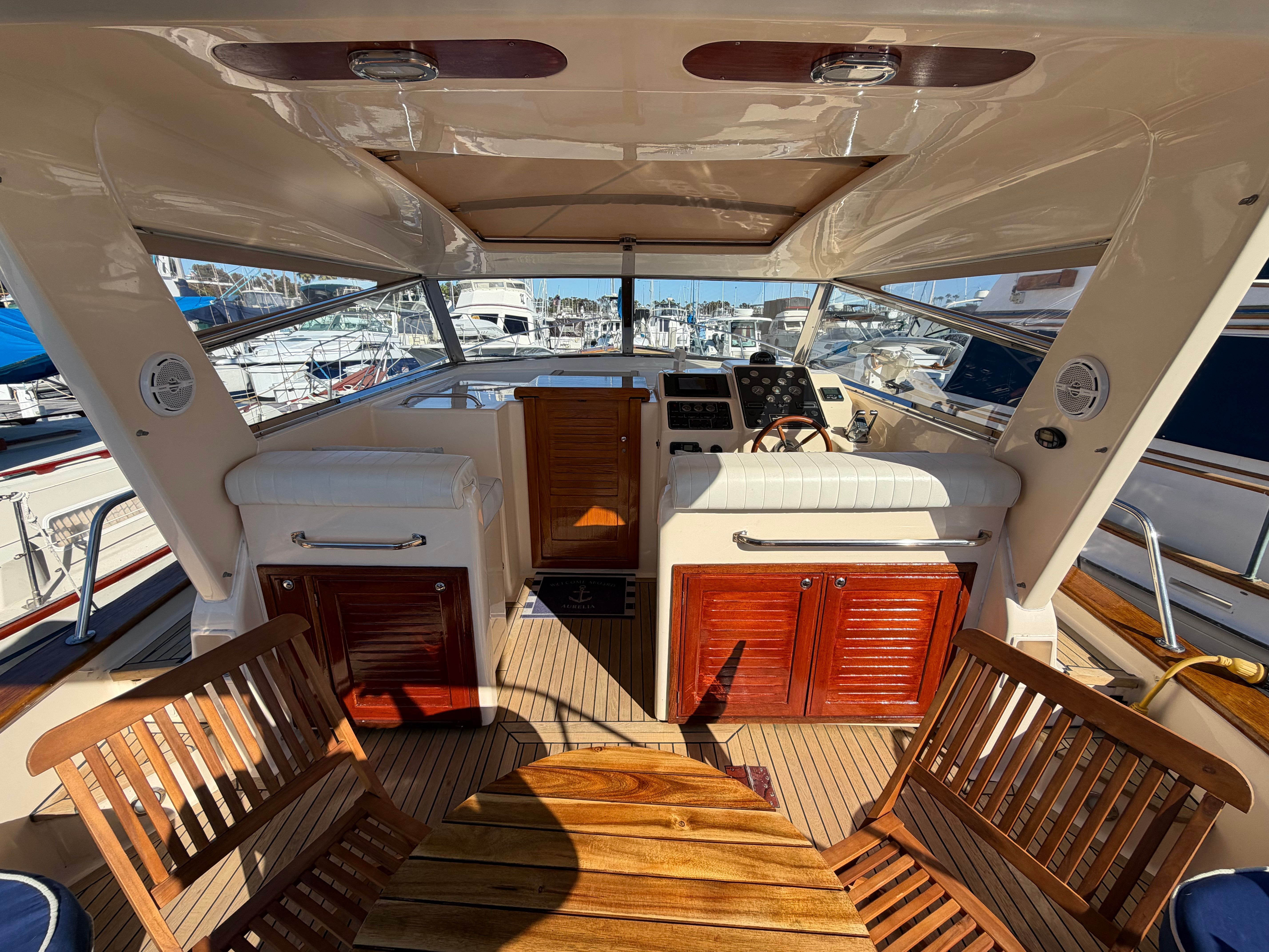 The cockpit of a 2003 Apreamare 11 with wooden furniture and a view of the marina.