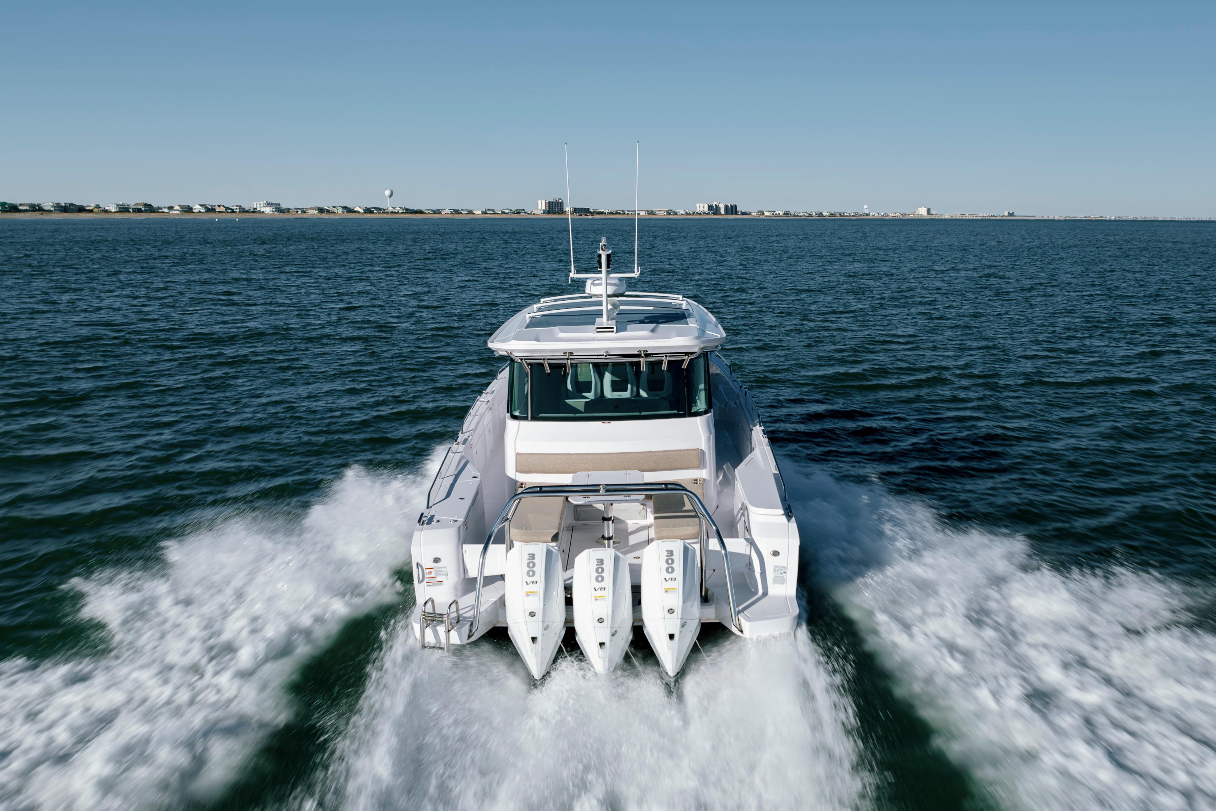 2027 Axopar 45 XC Cross Cabin cruising on open water, rear view.