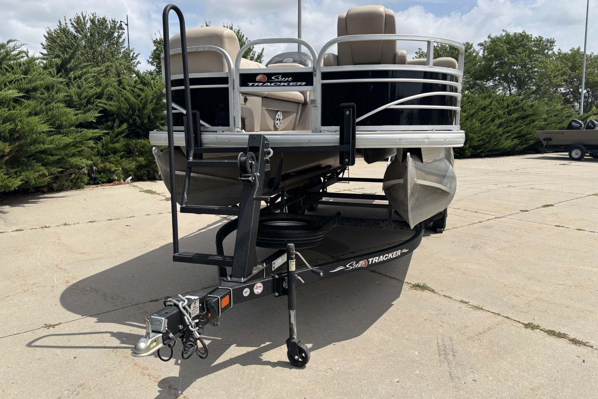 2023 Sun Tracker SportFish 20 DLX pontoon boat on trailer, parked outdoors.