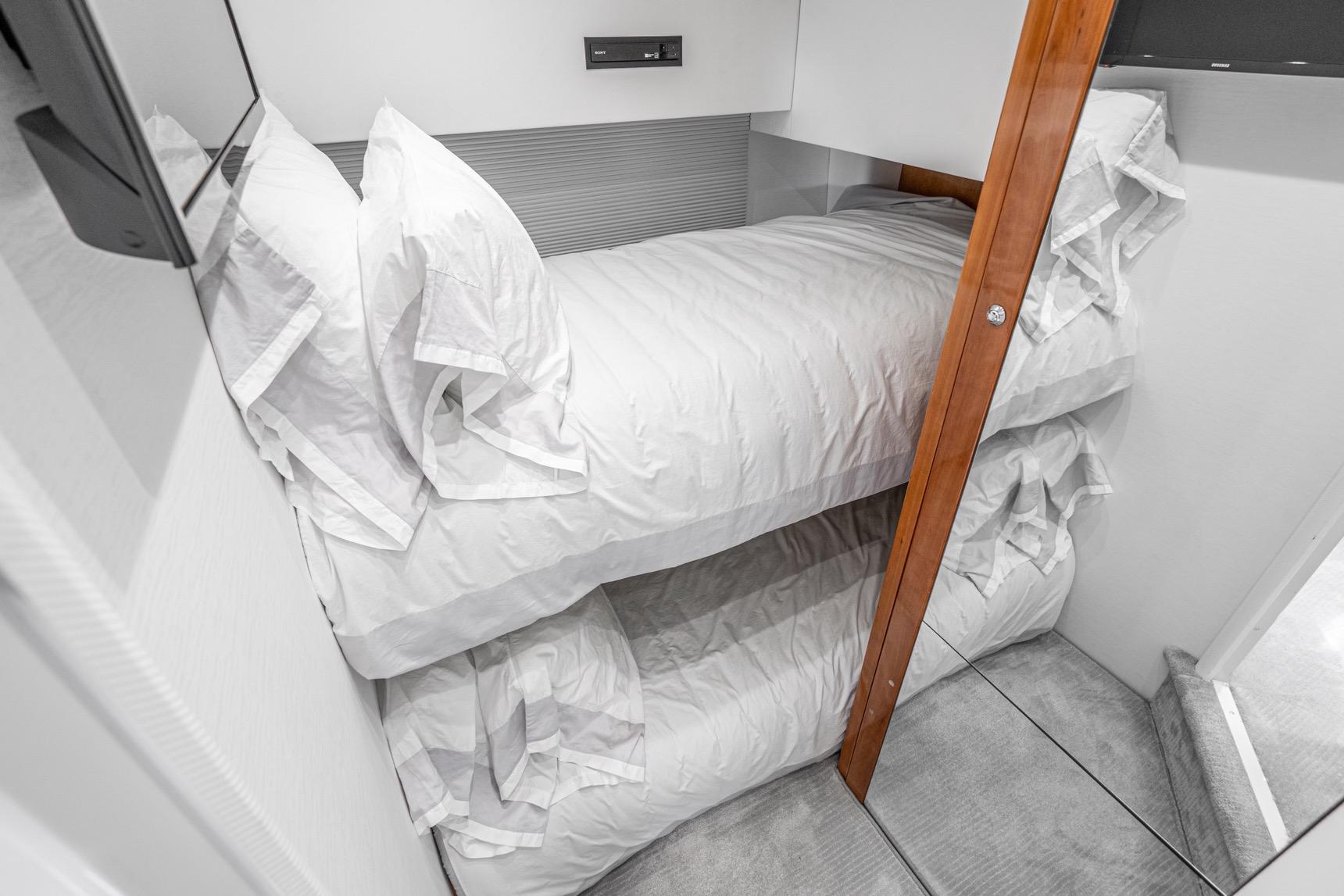 Bunk beds in 2021 Sunseeker Predator 68 yacht cabin, featuring white linens and wooden accents.