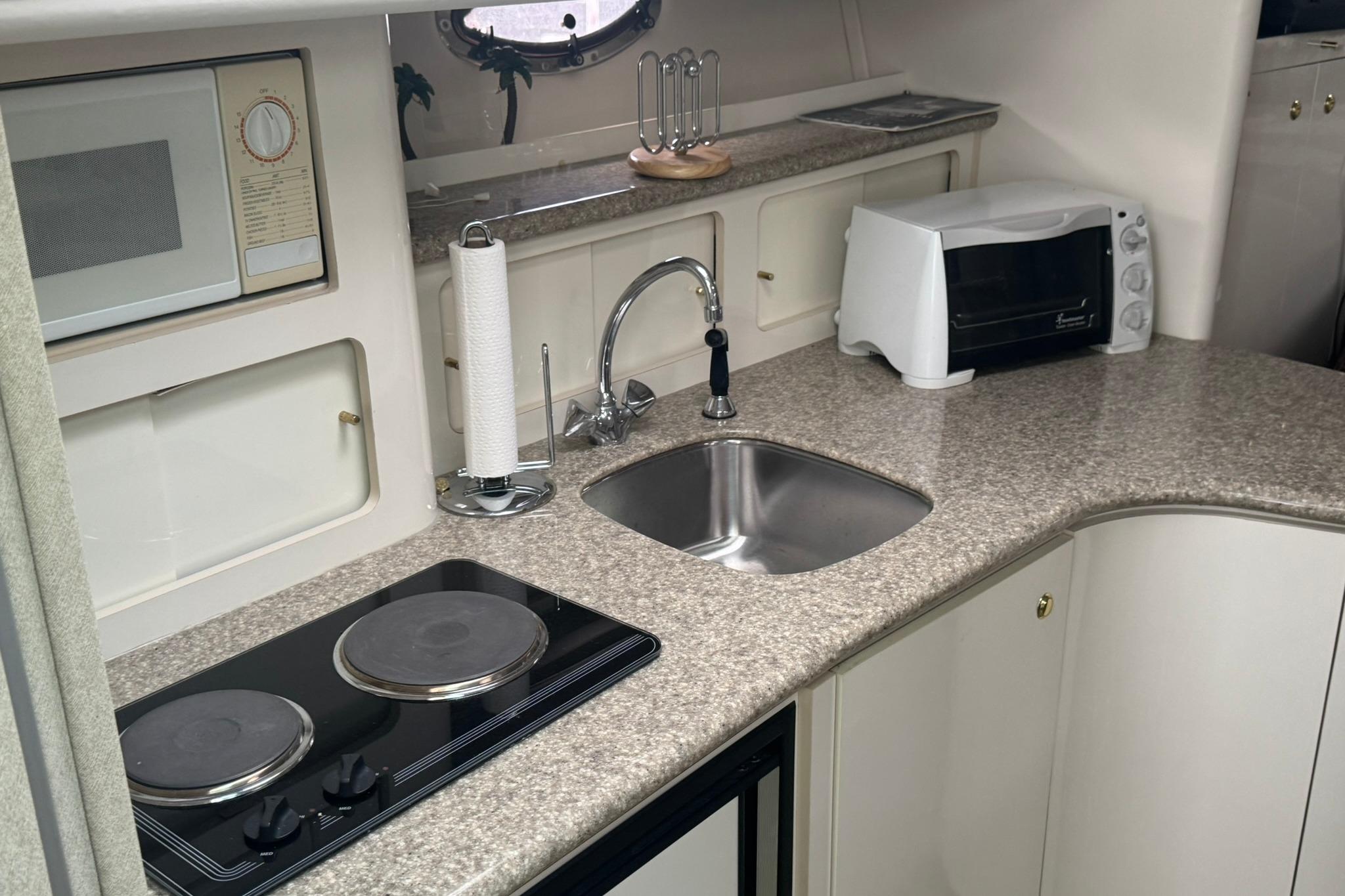 1998 Maxum 3700 SCR yacht kitchen with sink, stove, microwave, and toaster oven.
