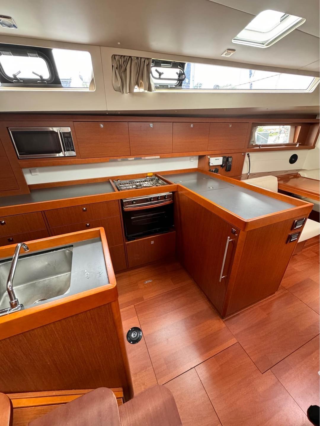 Interior of 2013 Beneteau Oceanis 48 yacht kitchen with wood finish and modern appliances.