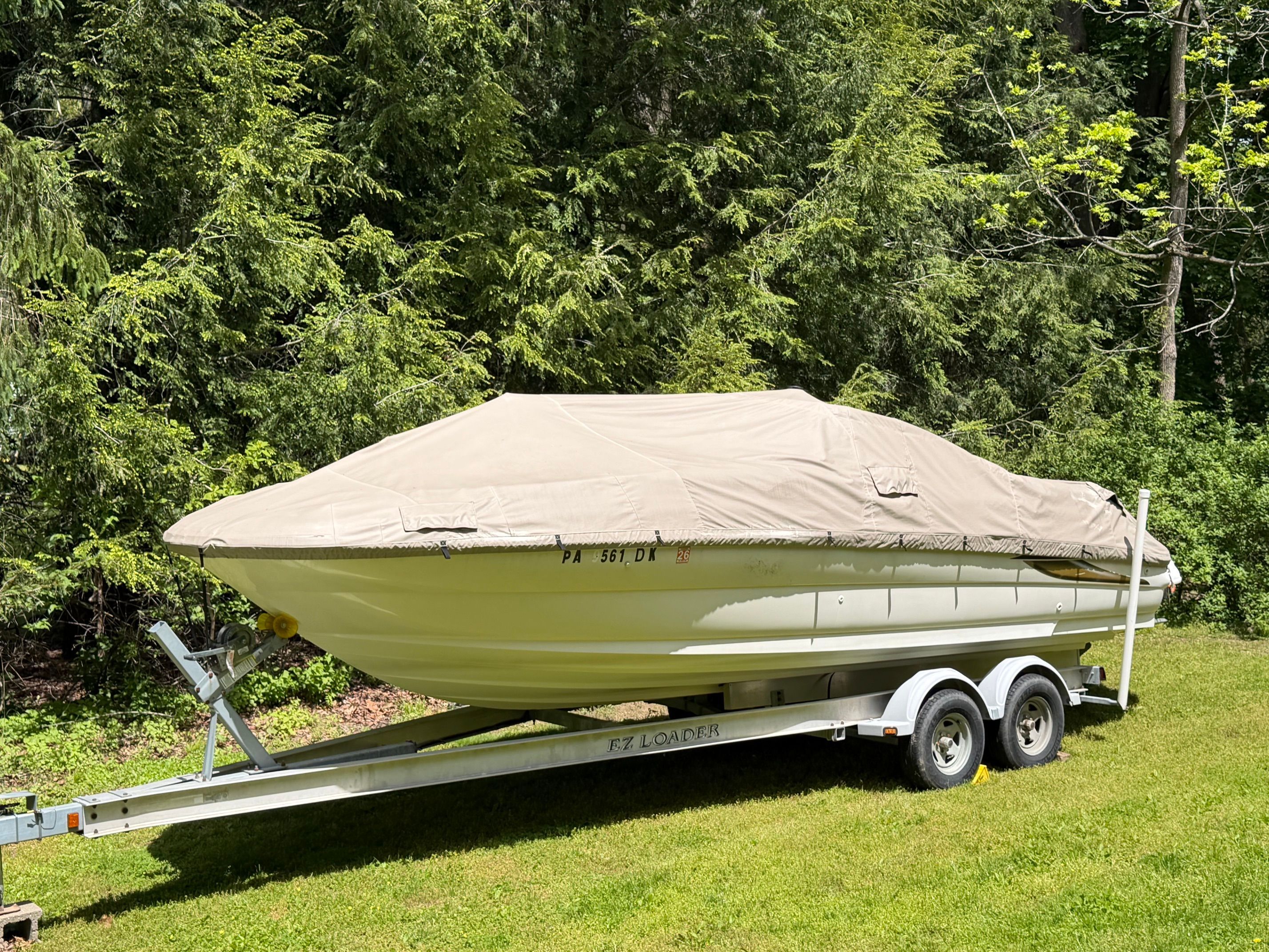 2001 Sea Ray 240 Sundeck boat covered on trailer in forest.