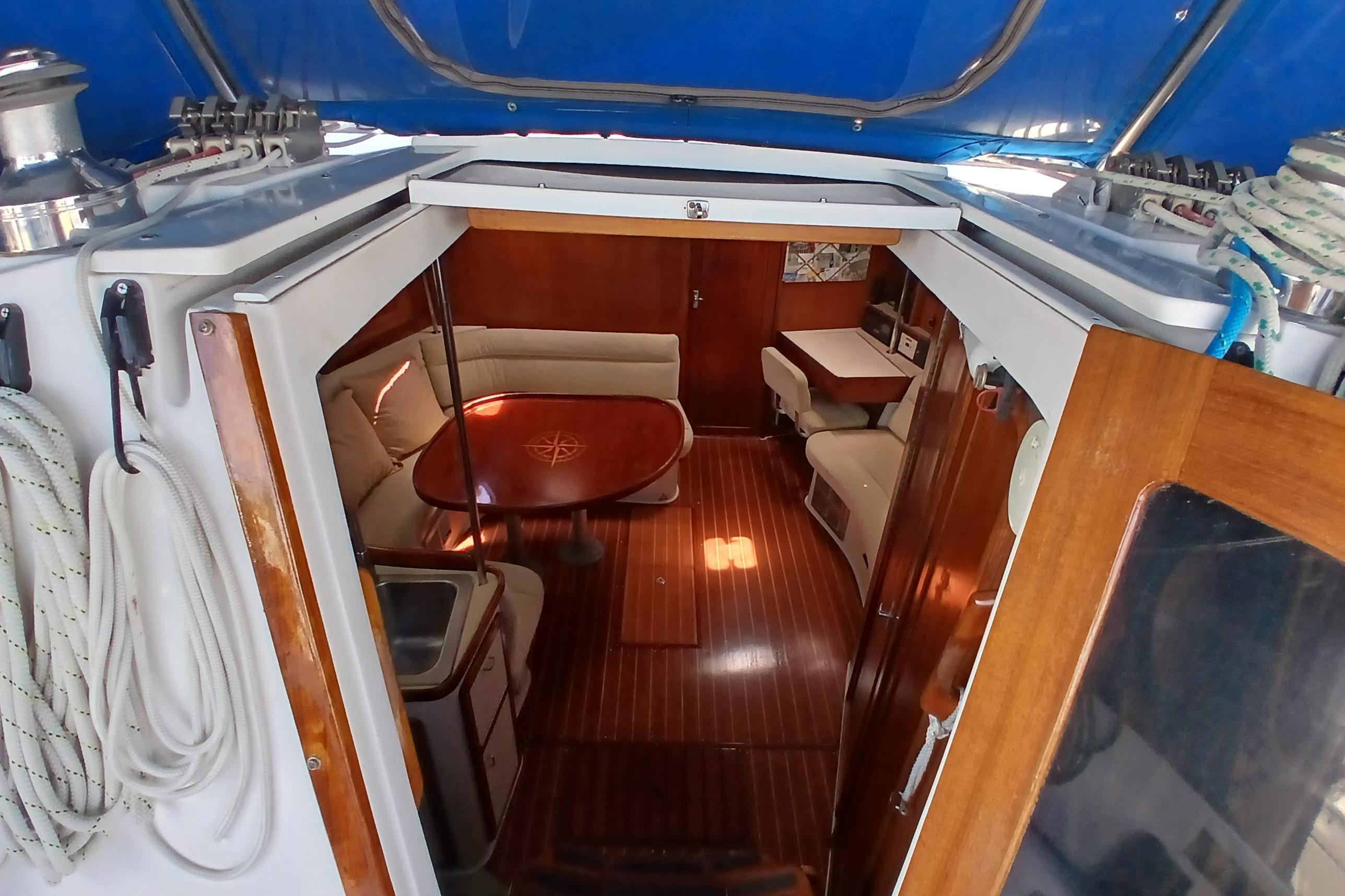 Interior view of 1995 Catalina 42 MkII sailboat with cozy seating and wooden flooring.