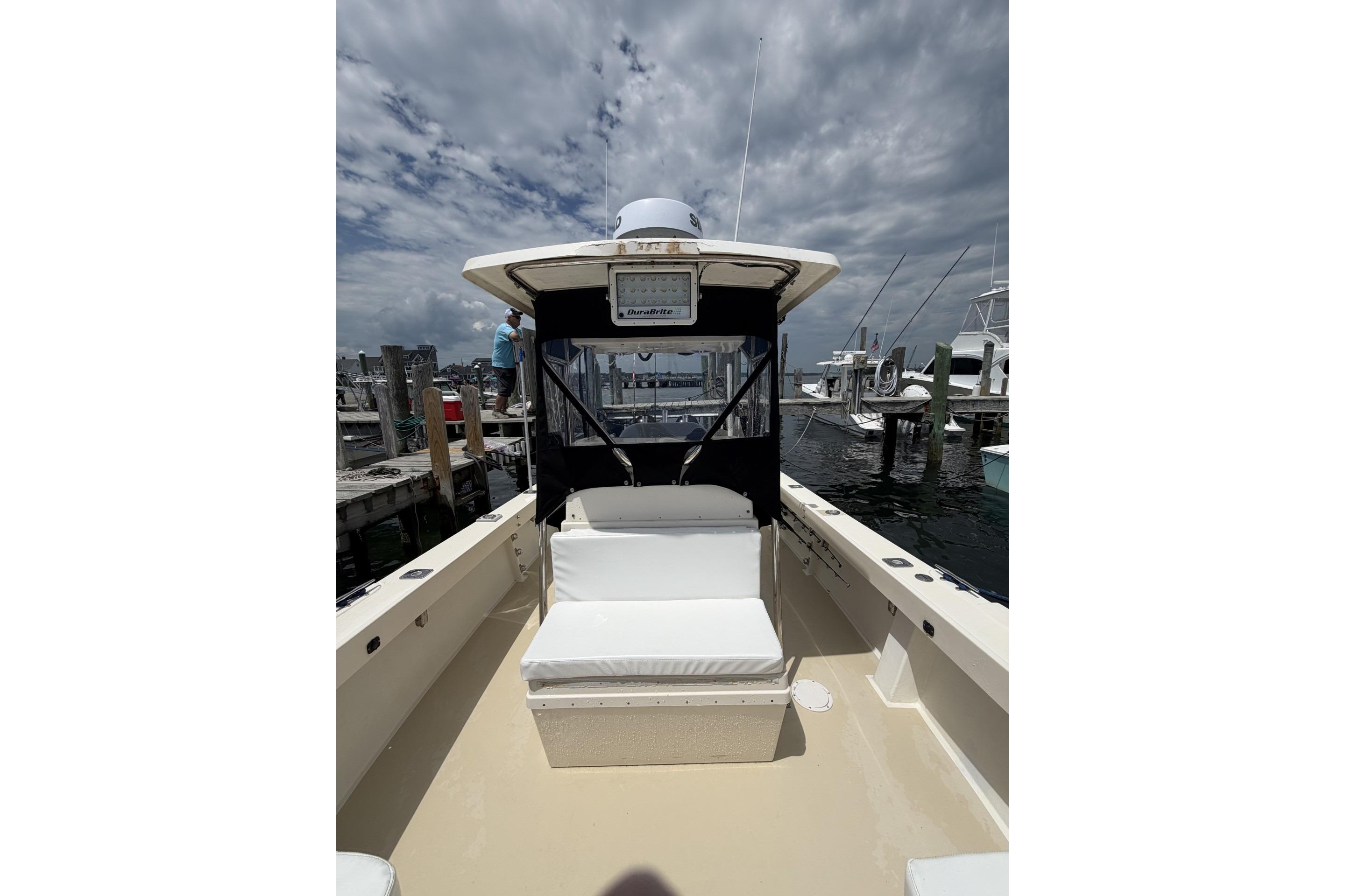 1999 Parker 2501 Center Console boat docked at marina under cloudy sky.