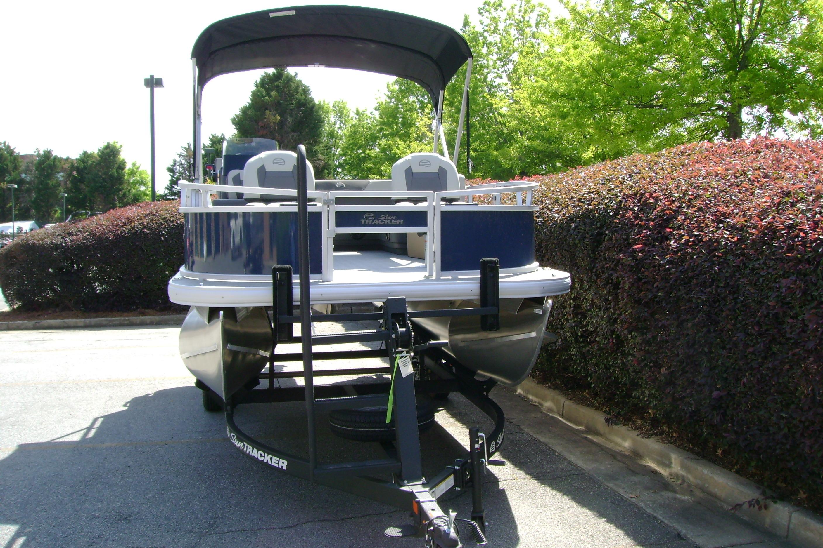 2026 Sun Tracker Bass Buggy 16 XL Select pontoon boat on trailer, parked outdoors.