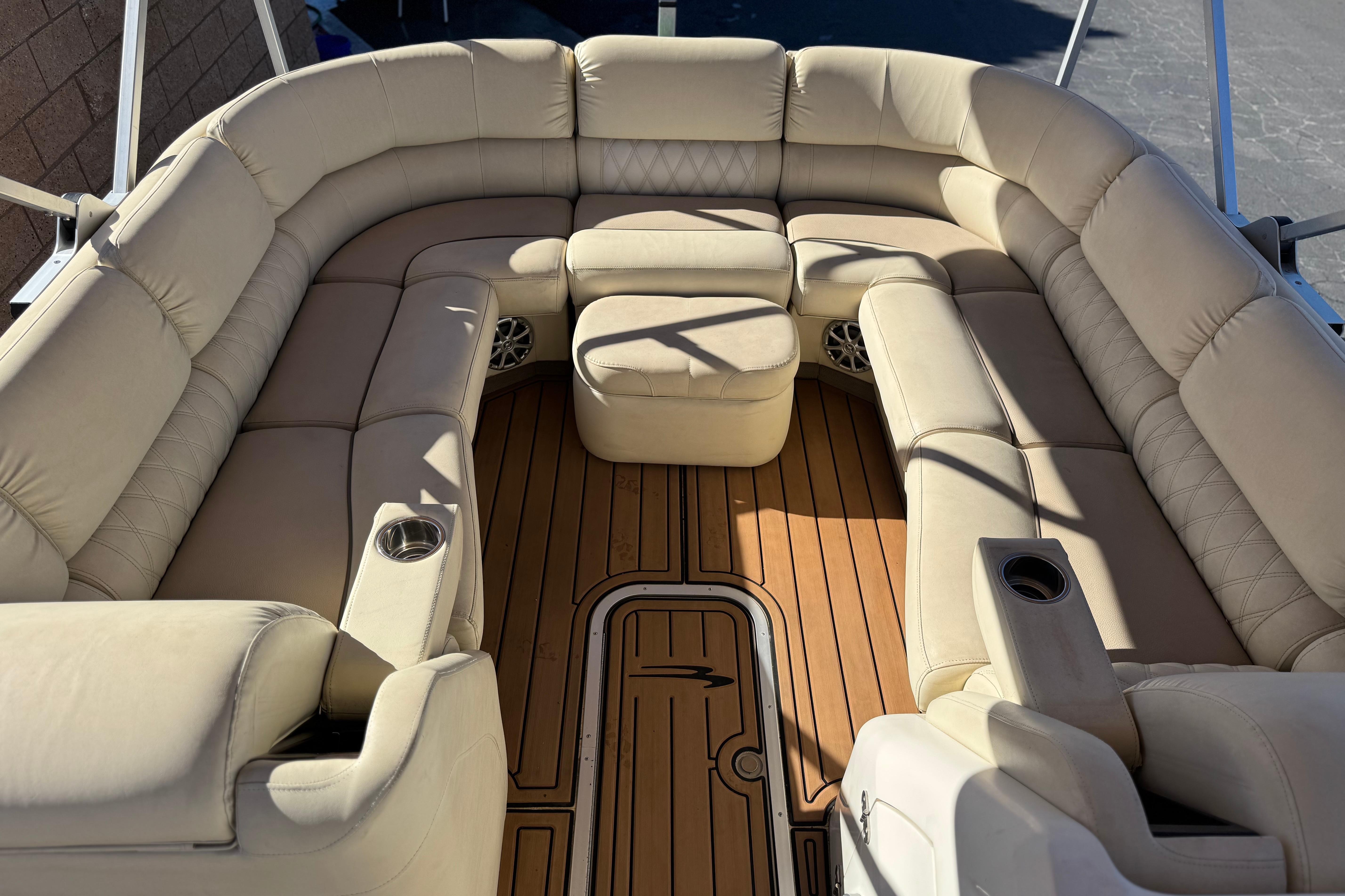 Luxurious seating on 2013 Bennington 2575QCW I/O boat with tan upholstery and wood flooring.