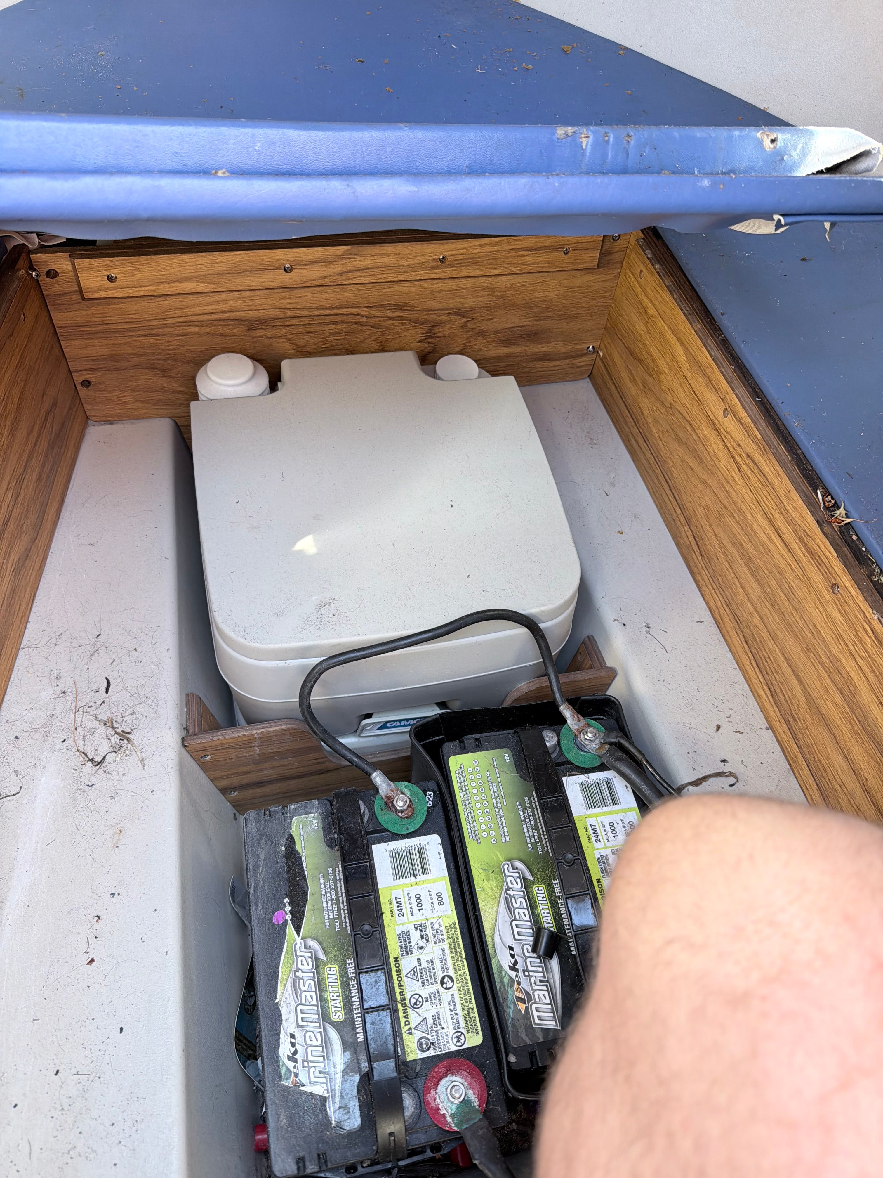 Interior view of a boat with batteries and a portable toilet.