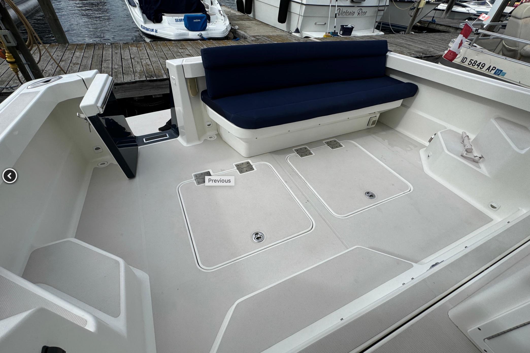 2008 Back Cove 33 boat deck with blue seating, docked at marina.