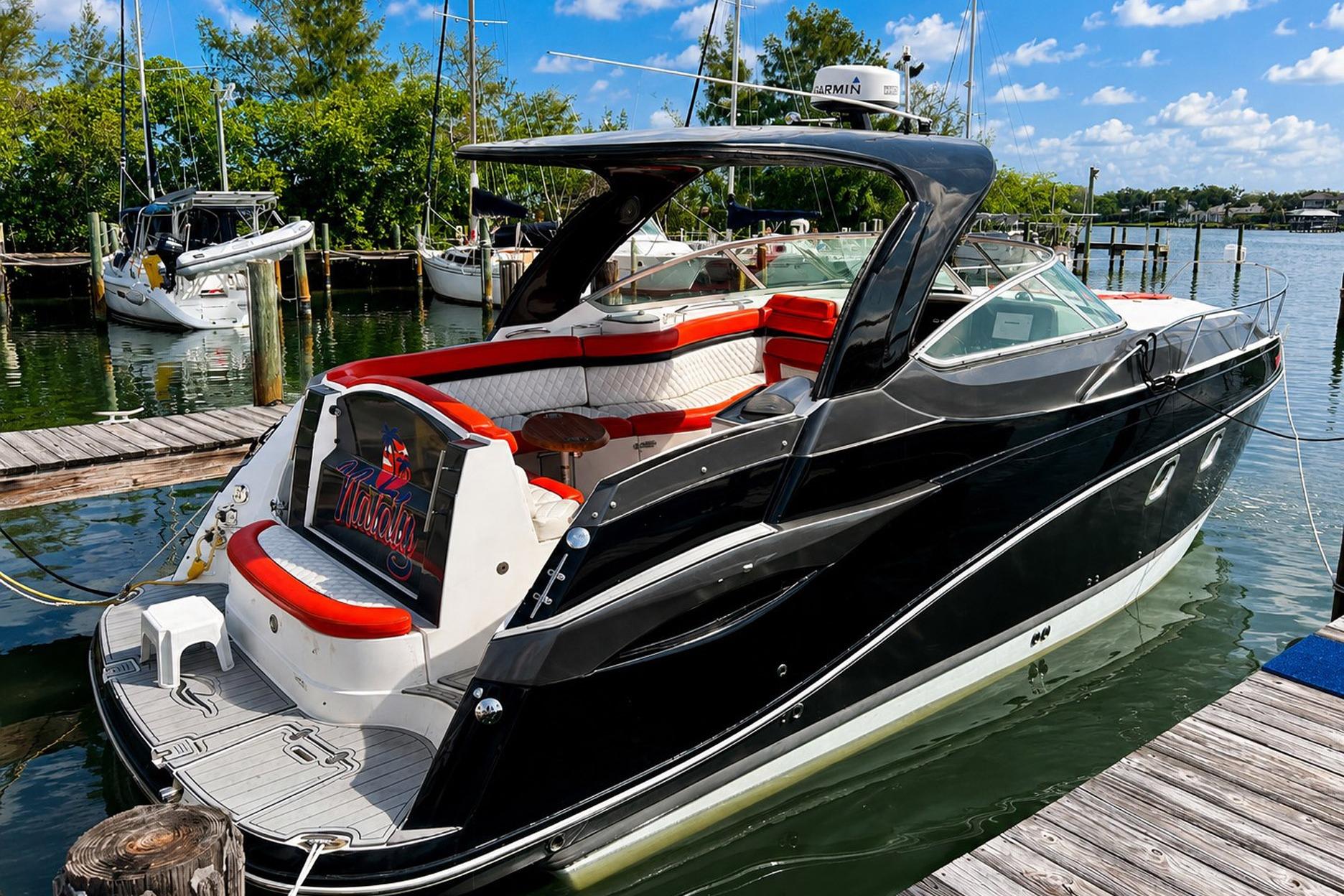 2012 Rinker 310 Express Cruiser LE docked, featuring sleek black design and spacious seating.