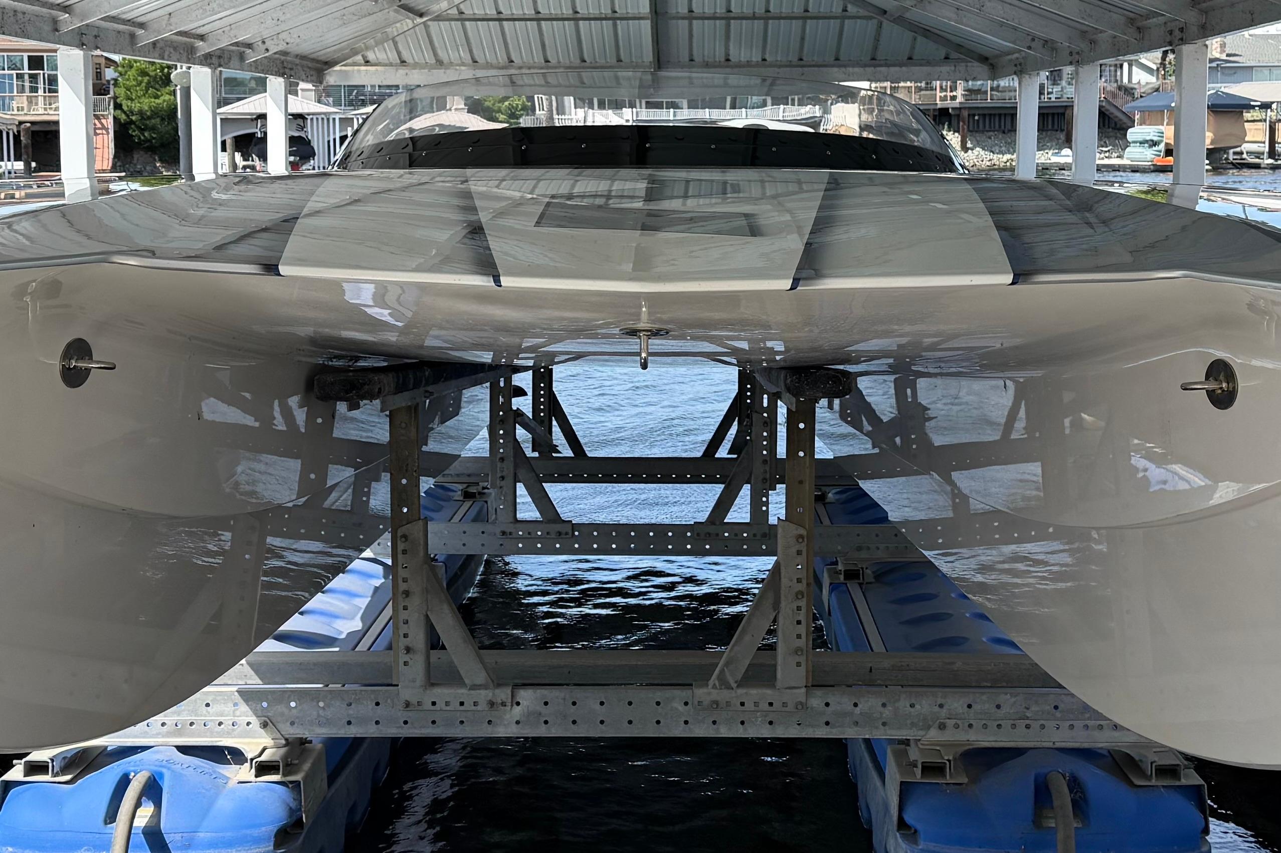 2018 MTI 340X boat on lift under covered dock, showcasing sleek hull design.